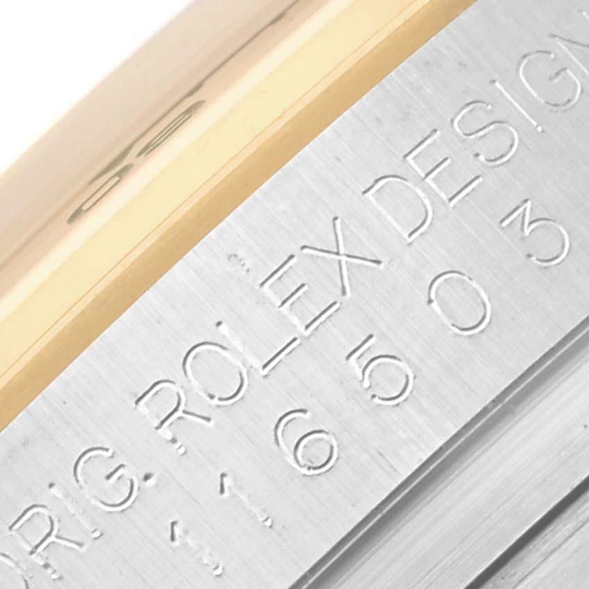 The image shows a close-up of the Rolex Daytona 116503 Men's Steel and Gold (two tone) White Dial 116503 Men's Steel and Gold (two tone) White Dial's side case with engraved text and the bezel's edge.