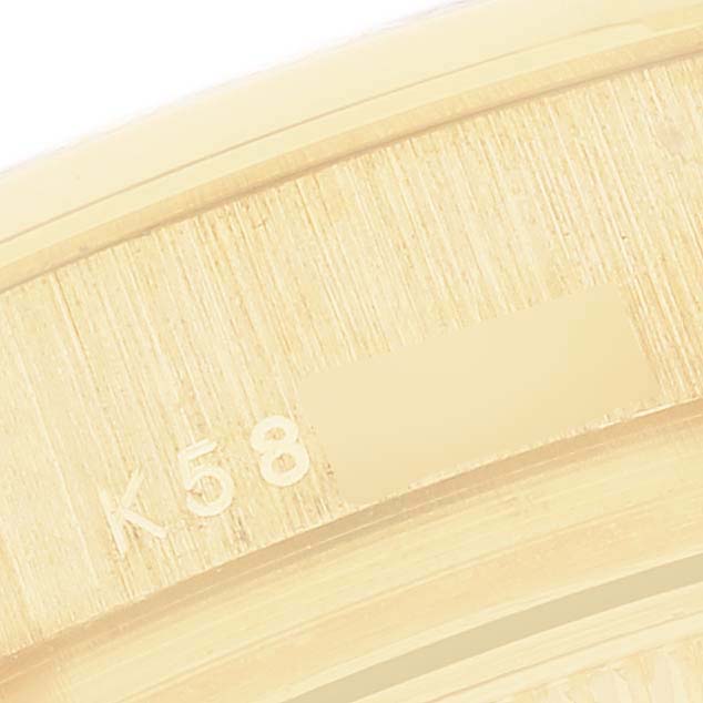The image shows a close-up of a Rolex Pearlmaster 80298 Women's Yellow Gold Black Dial watch's gold case edge with engraved markings.