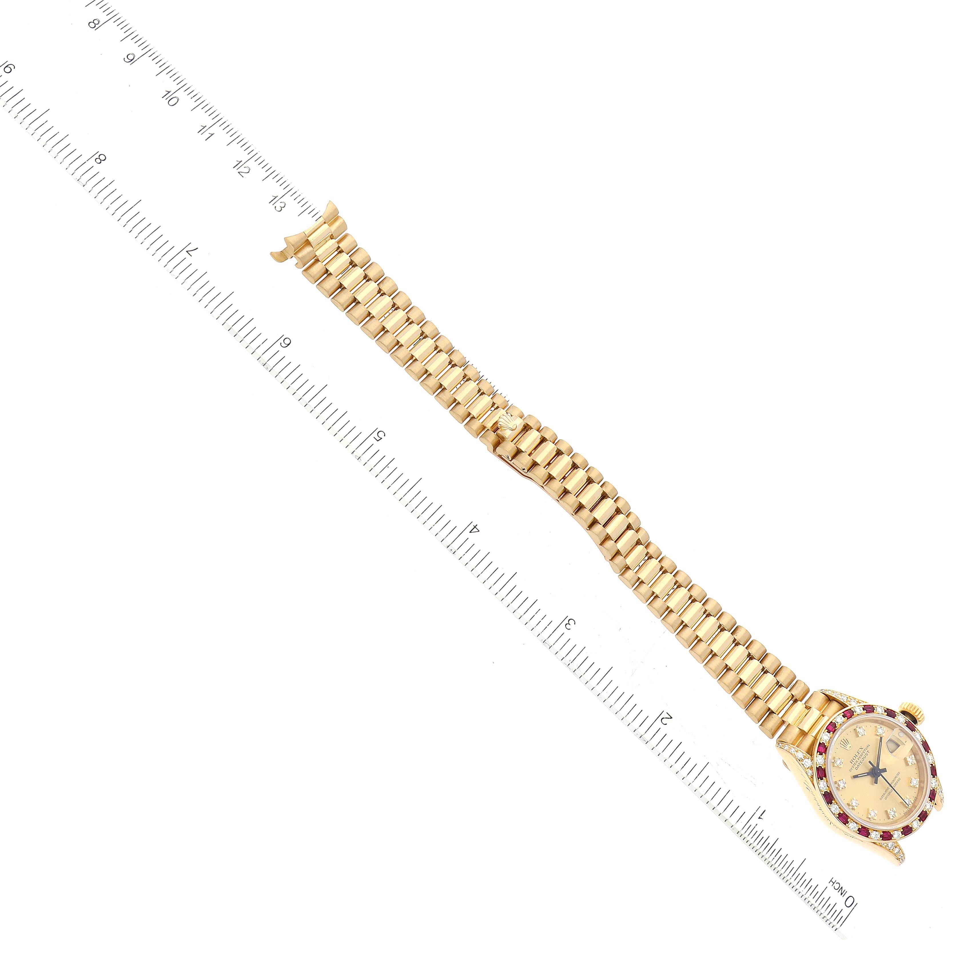 The image shows a Rolex President 69198 Women
s Yellow Gold Champagne Dial 69198 Women
s Yellow Gold Champagne Dial model watch laid flat with a ruler for scale, highlighting the watch face and the bracelet.