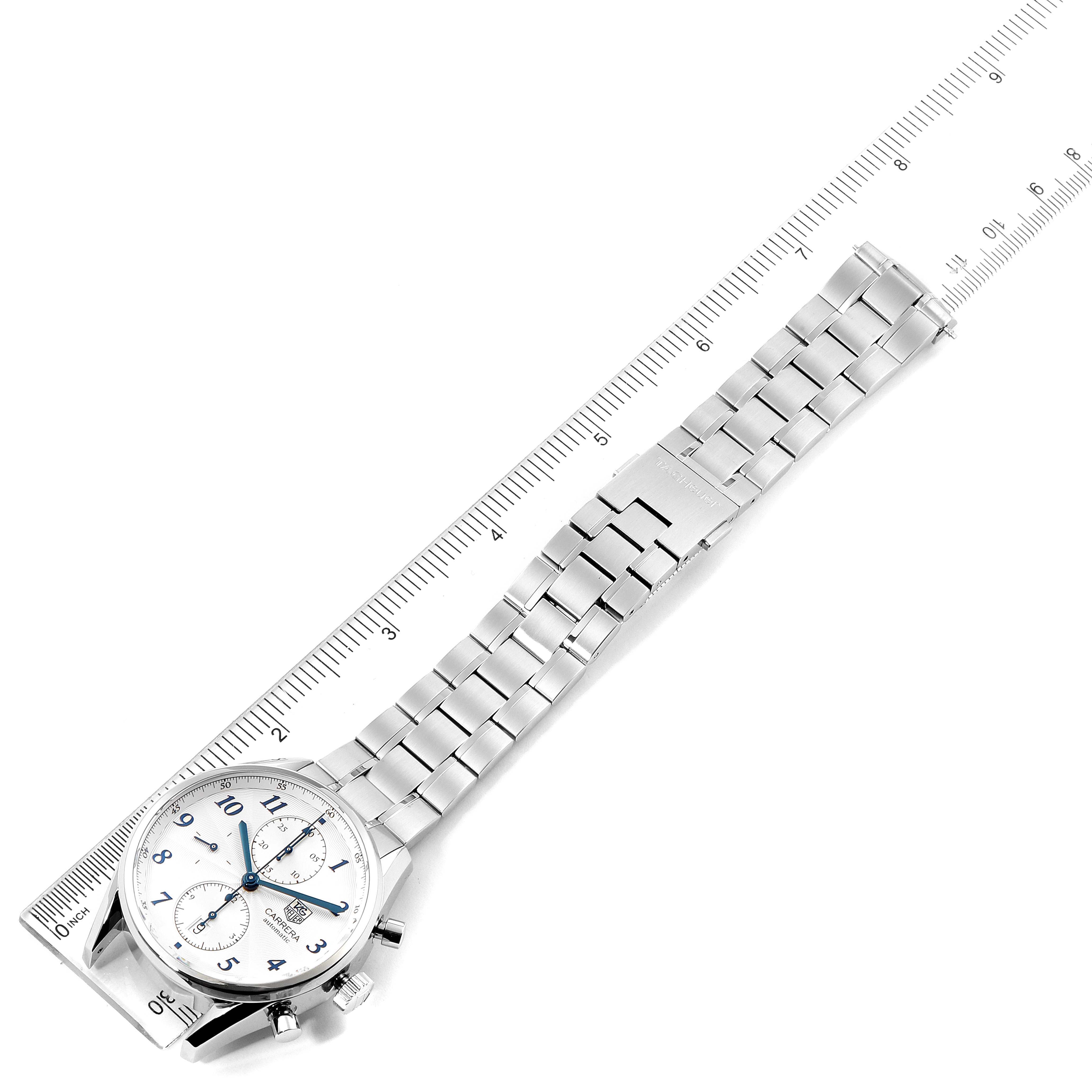 The image shows a top-down view of a Tag Heuer Carrera CAS2111.BA0730 Men
s Stainless Steel Silver Dial CAS2111.BA0730 Men
s Stainless Steel Silver Dial watch, displaying its face and metal bracelet next to a ruler.