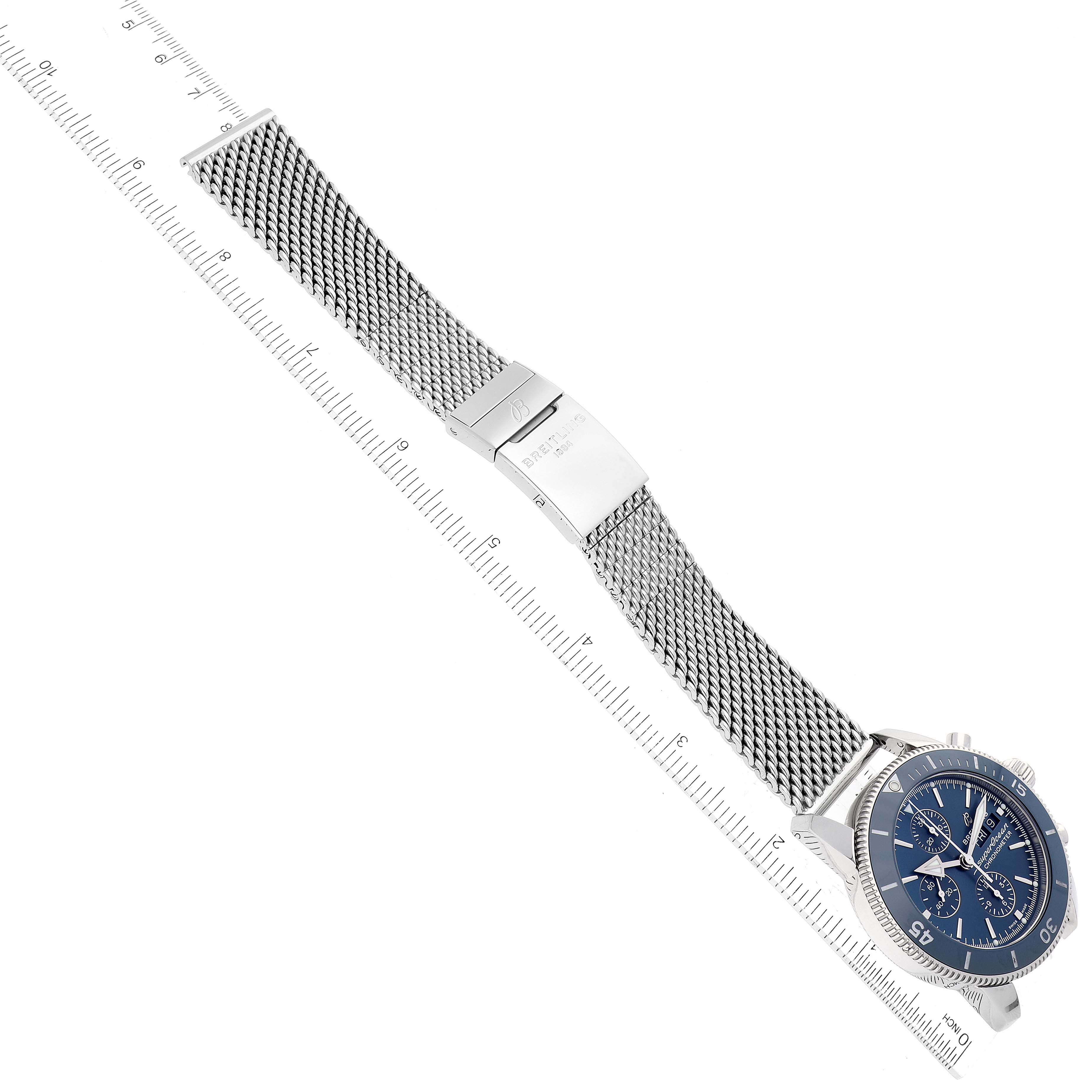 The image shows a top view of a Breitling Superocean A13313 Men's Stainless Steel Blue Dial A13313 Men's Stainless Steel Blue Dial watch, displaying its blue dial, steel mesh bracelet, and clasp, alongside a ruler for scale.