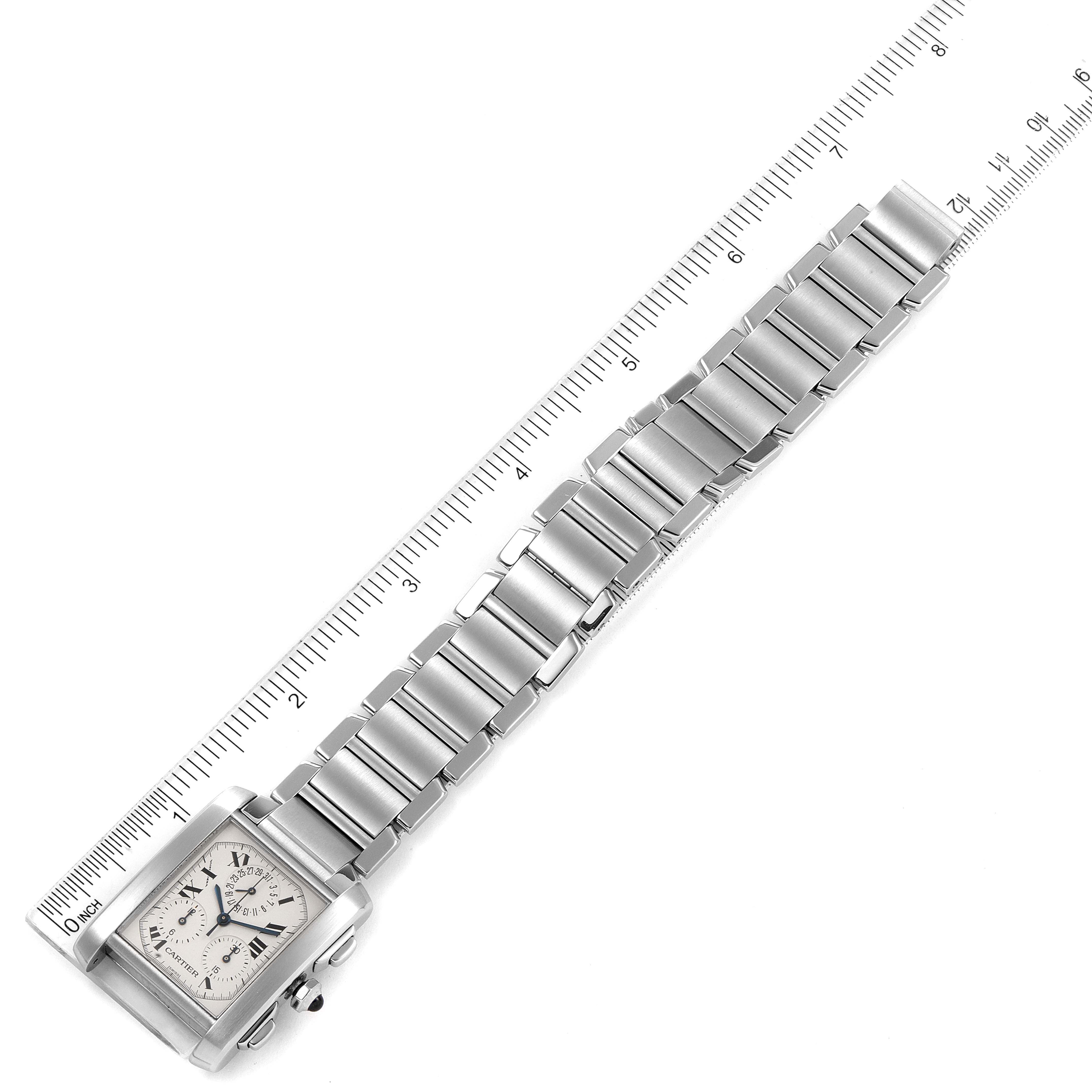 This image shows a Tank Française model by Cartier from an overhead angle, highlighting the watch dial and metal bracelet alongside a ruler.