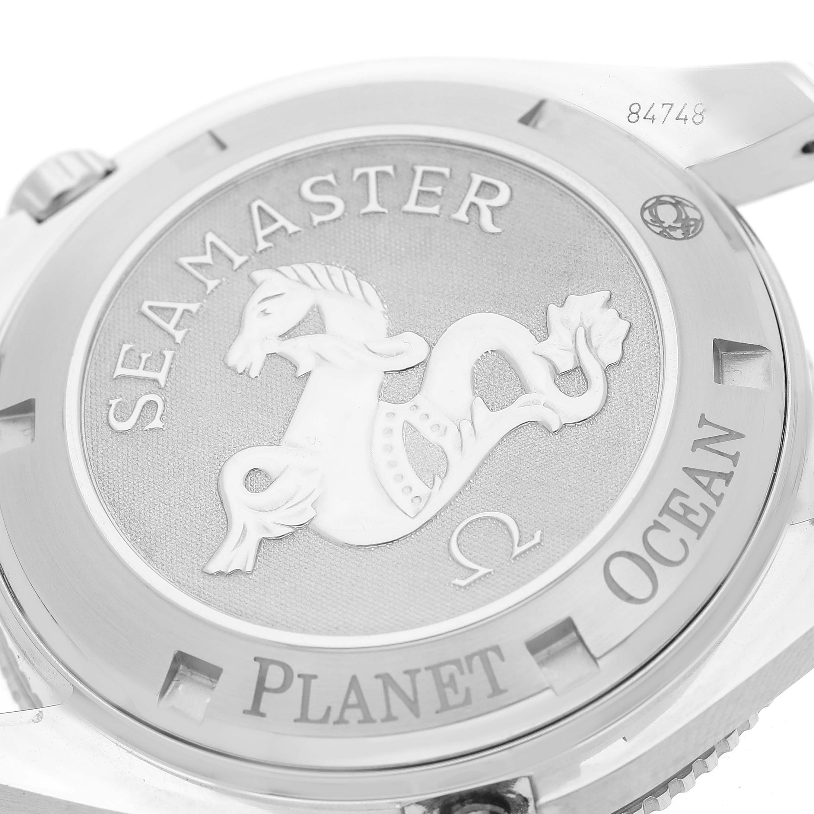 The image shows the case back of the Omega Seamaster Planet Ocean watch at a slight angle, displaying the engraved logo.