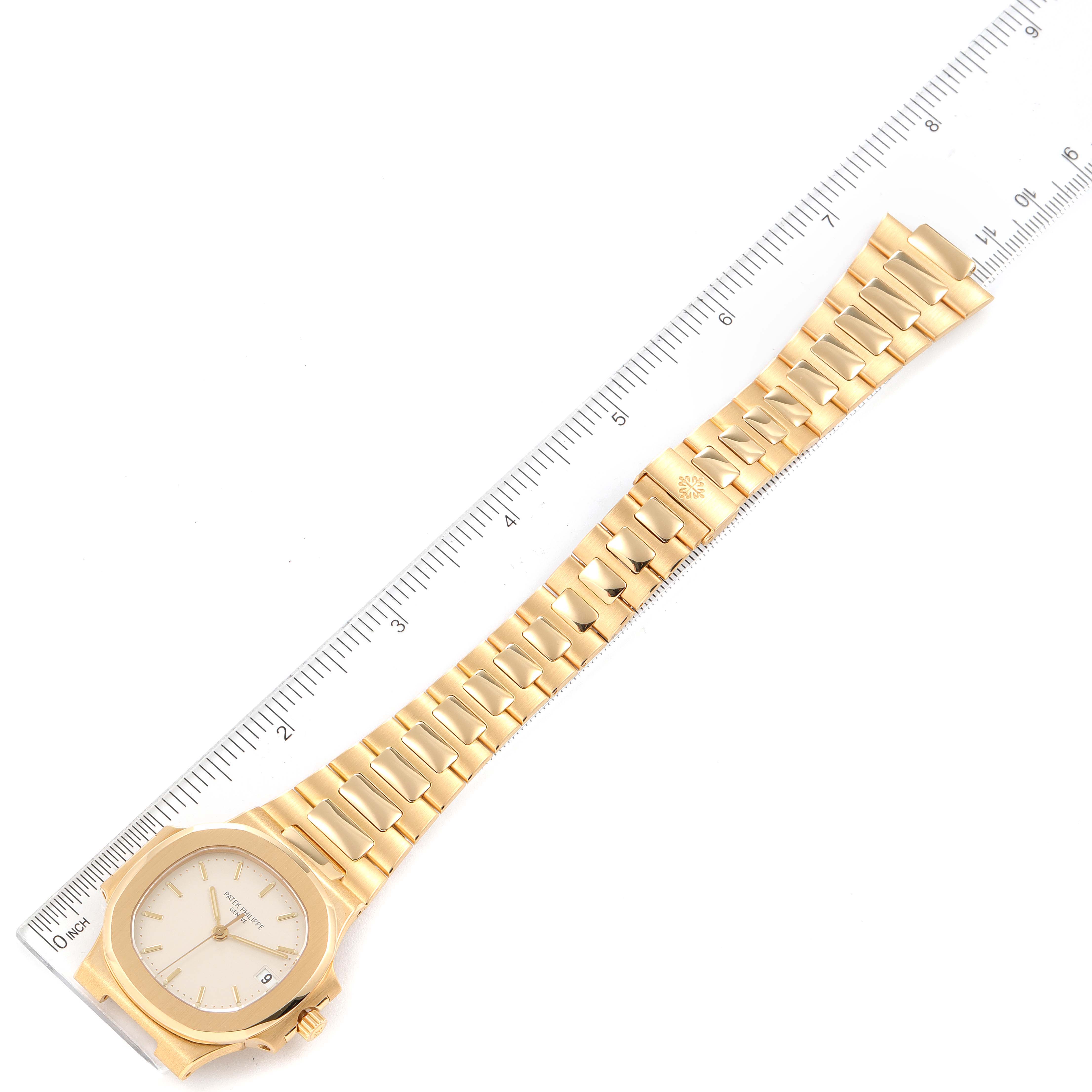 The image shows a top-down view of the entire gold Nautilus watch by Patek Philippe with a ruler for scale.