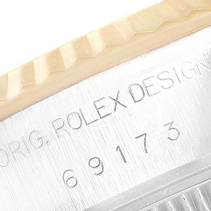 The image shows a close-up of the edge of a Rolex Datejust 69173 Women's Steel and Gold (two tone) Champagne Dial 69173 Women's Steel and Gold (two tone) Champagne Dial watch case, specifically highlighting the engraved serial number and part of the fluted bezel.