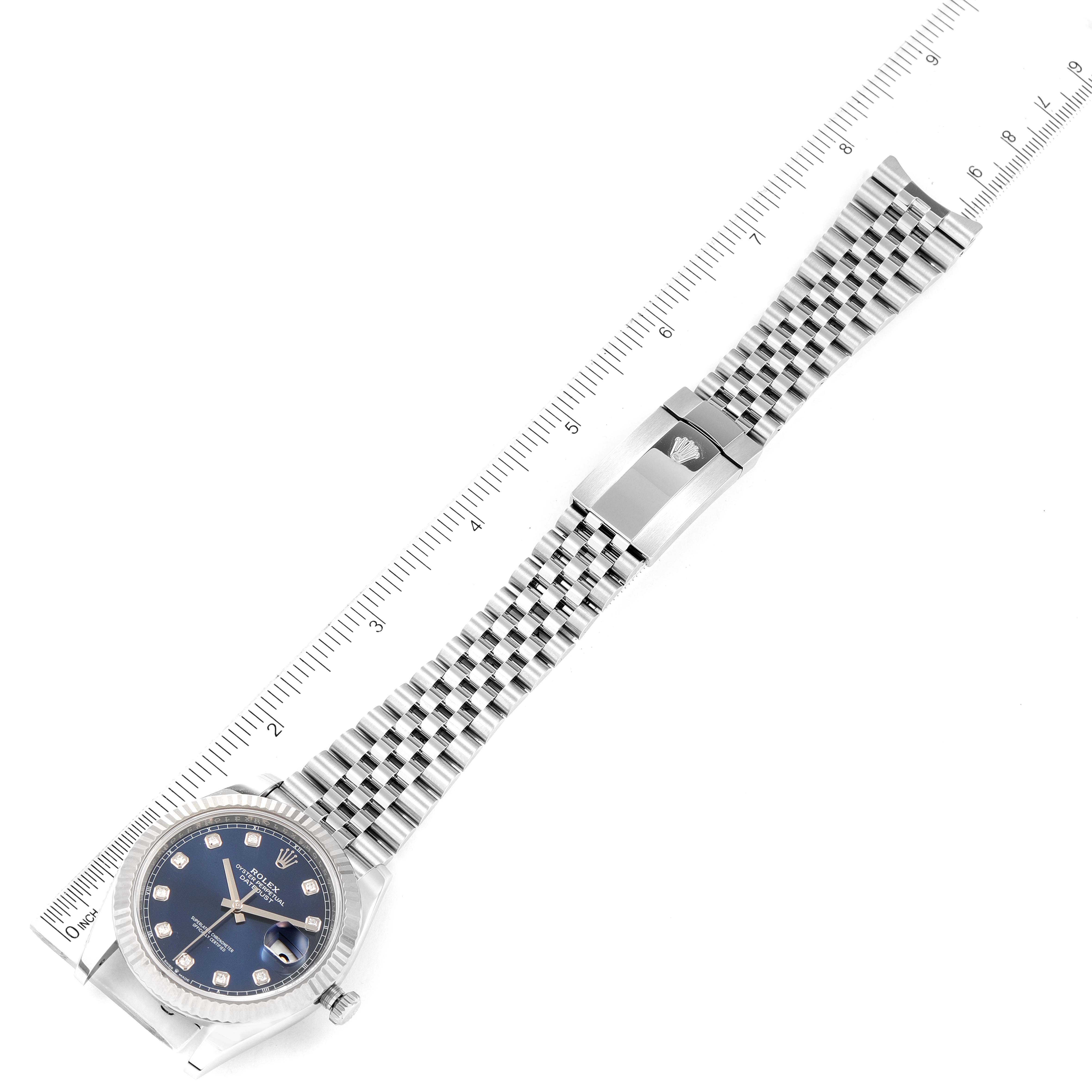 The Rolex Datejust 41 126334 Men's Stainless Steel Blue Dial 126334 Men's Stainless Steel Blue Dial watch is displayed at a top-down angle, showing the watch face, bracelet, and clasp against a ruler.