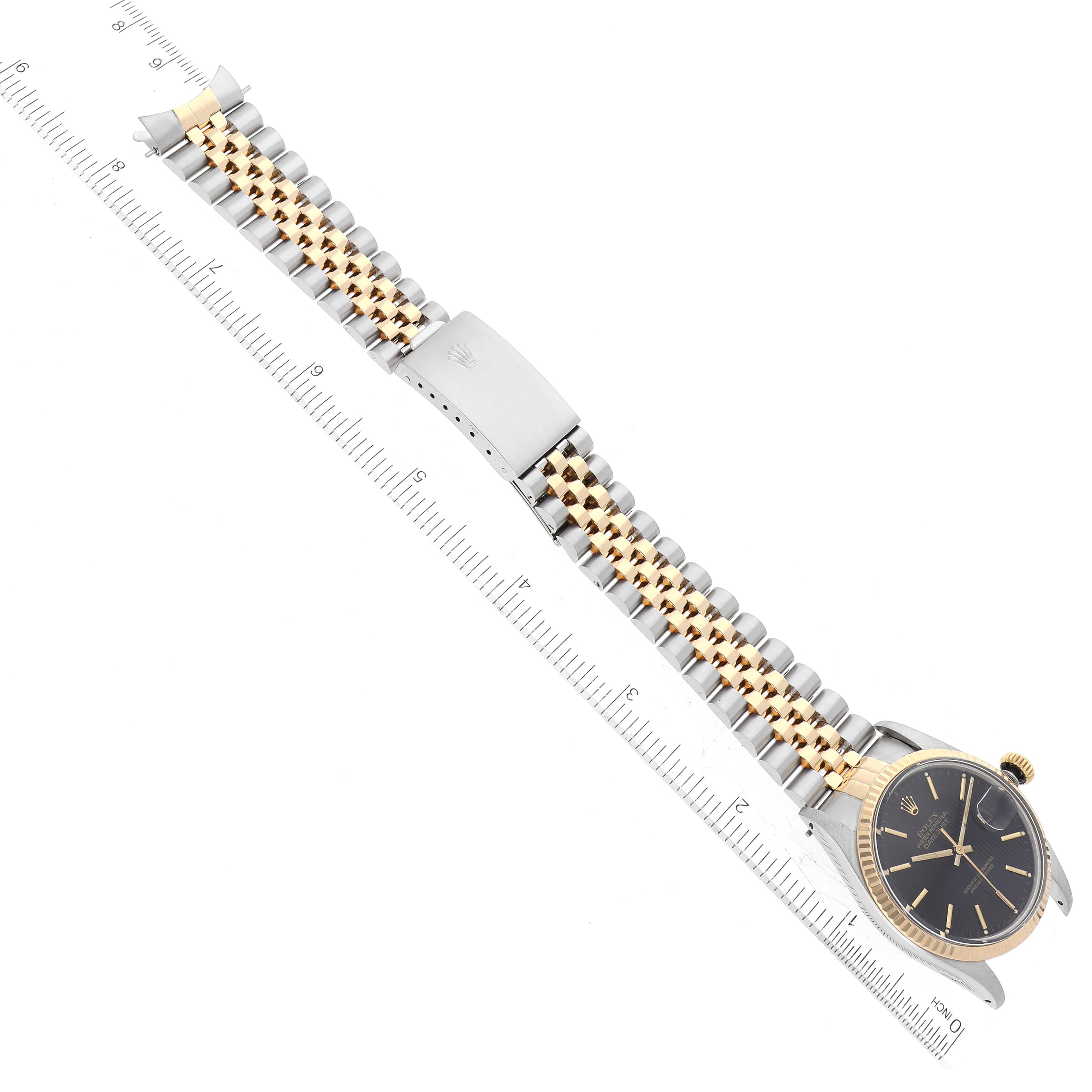 The Vintage Collection Rolex watch is shown lying flat with the face, bezel, band, and clasp visible, alongside a ruler for scale.