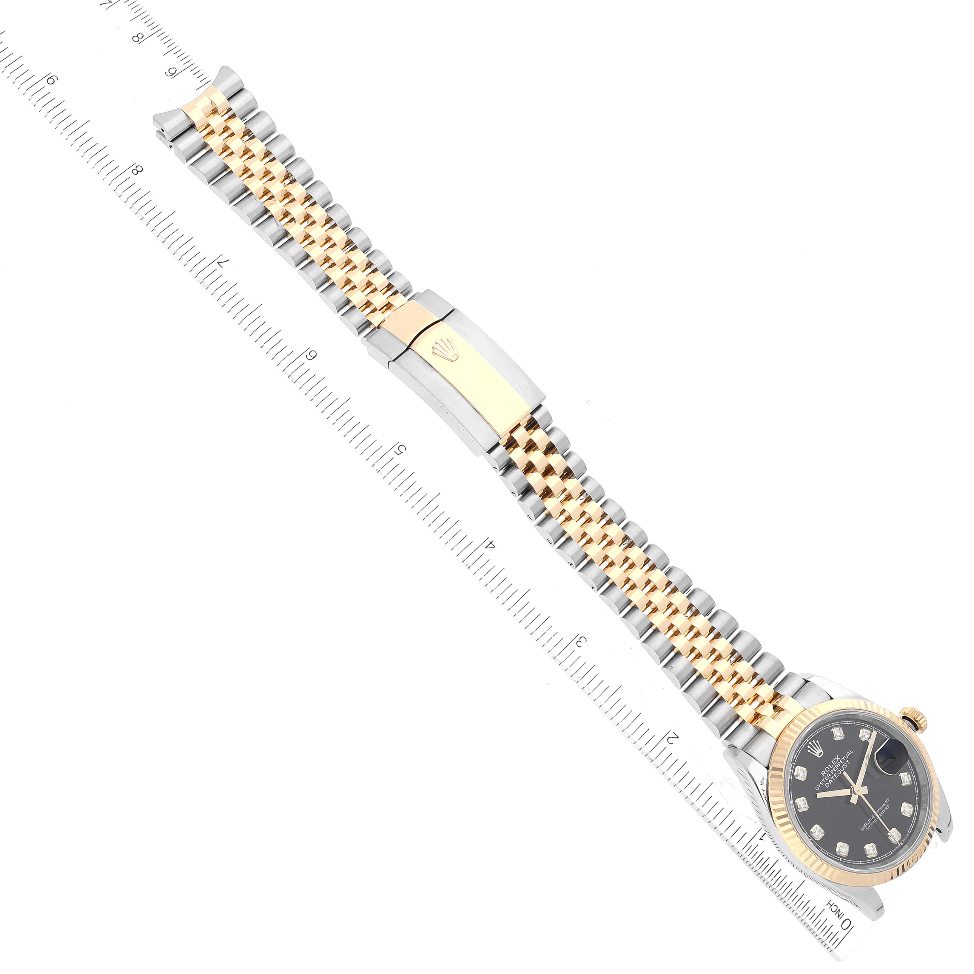 The image shows a top-down view of a Rolex Datejust 126233 Men's Steel and Gold (two tone) Black Dial 126233 Men's Steel and Gold (two tone) Black Dial watch, including its face, two-tone bracelet, and clasp, laid alongside a ruler.