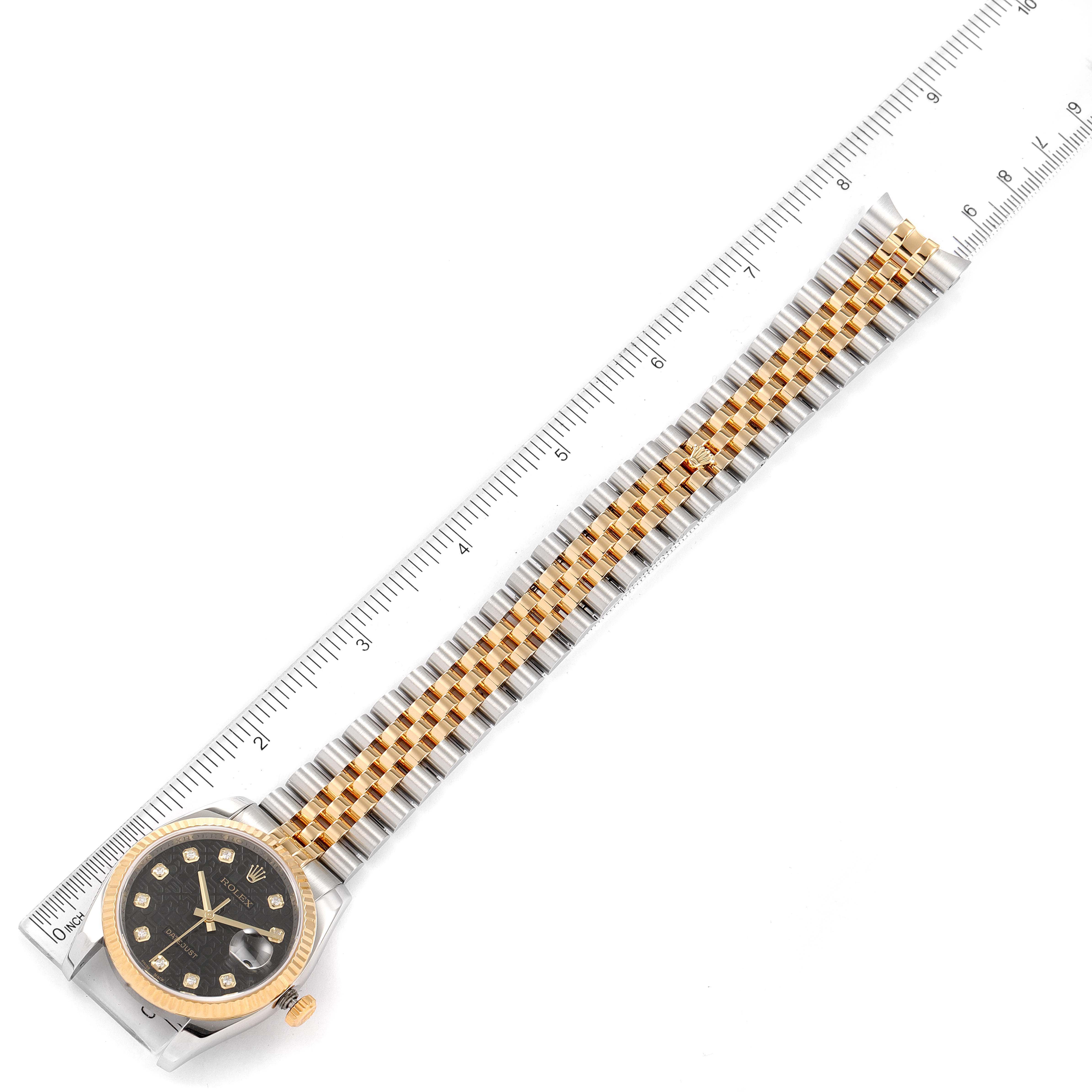 The Rolex Datejust 116233 Men's Steel and Gold (two tone) Black Dial 116233 Men's Steel and Gold (two tone) Black Dial watch is shown from a top-down angle alongside a ruler, displaying the watch face and two-tone bracelet.