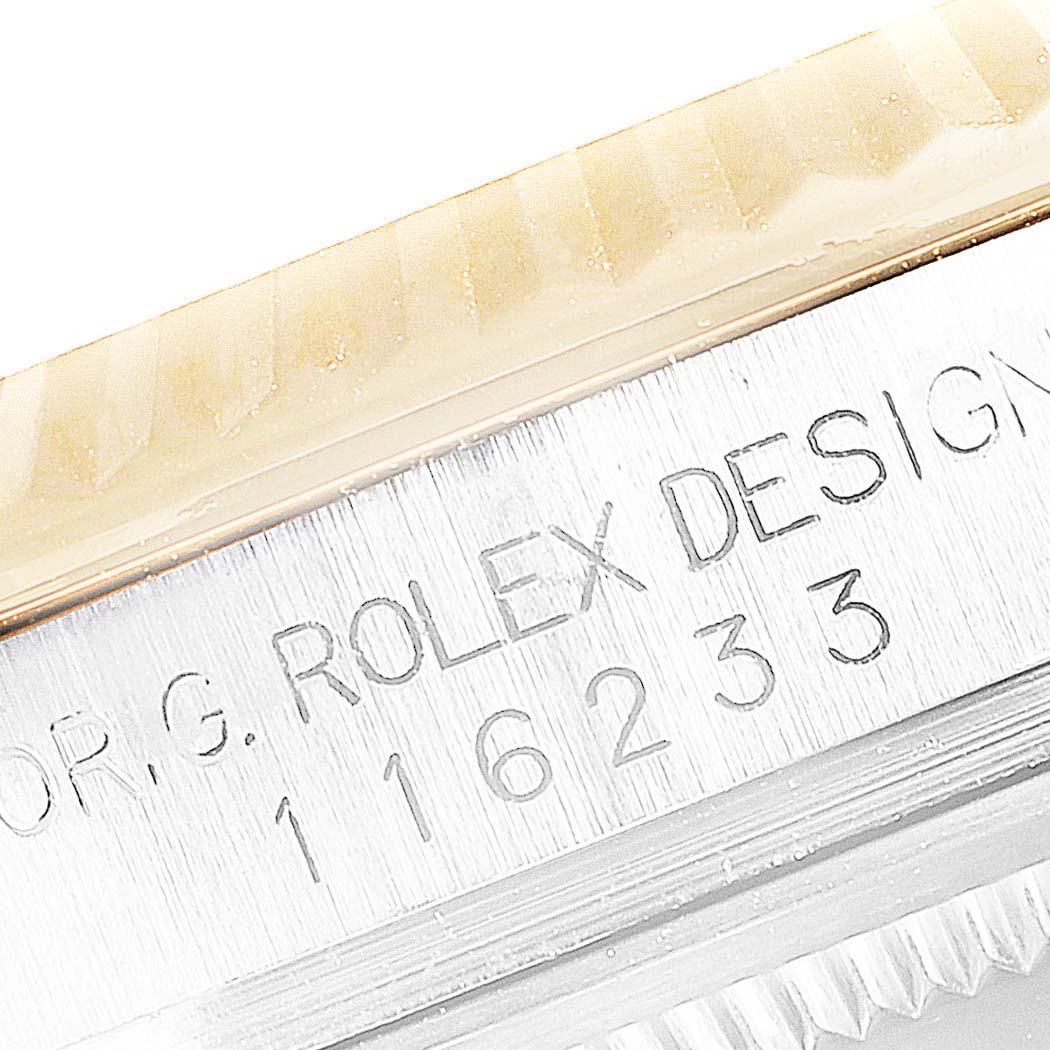 The image shows an engraved serial and model number on the side of a Rolex Datejust 116233 Men's Steel and Gold (two tone) Black Dial 116233 Men's Steel and Gold (two tone) Black Dial watch, focusing on its distinct bezel and case.