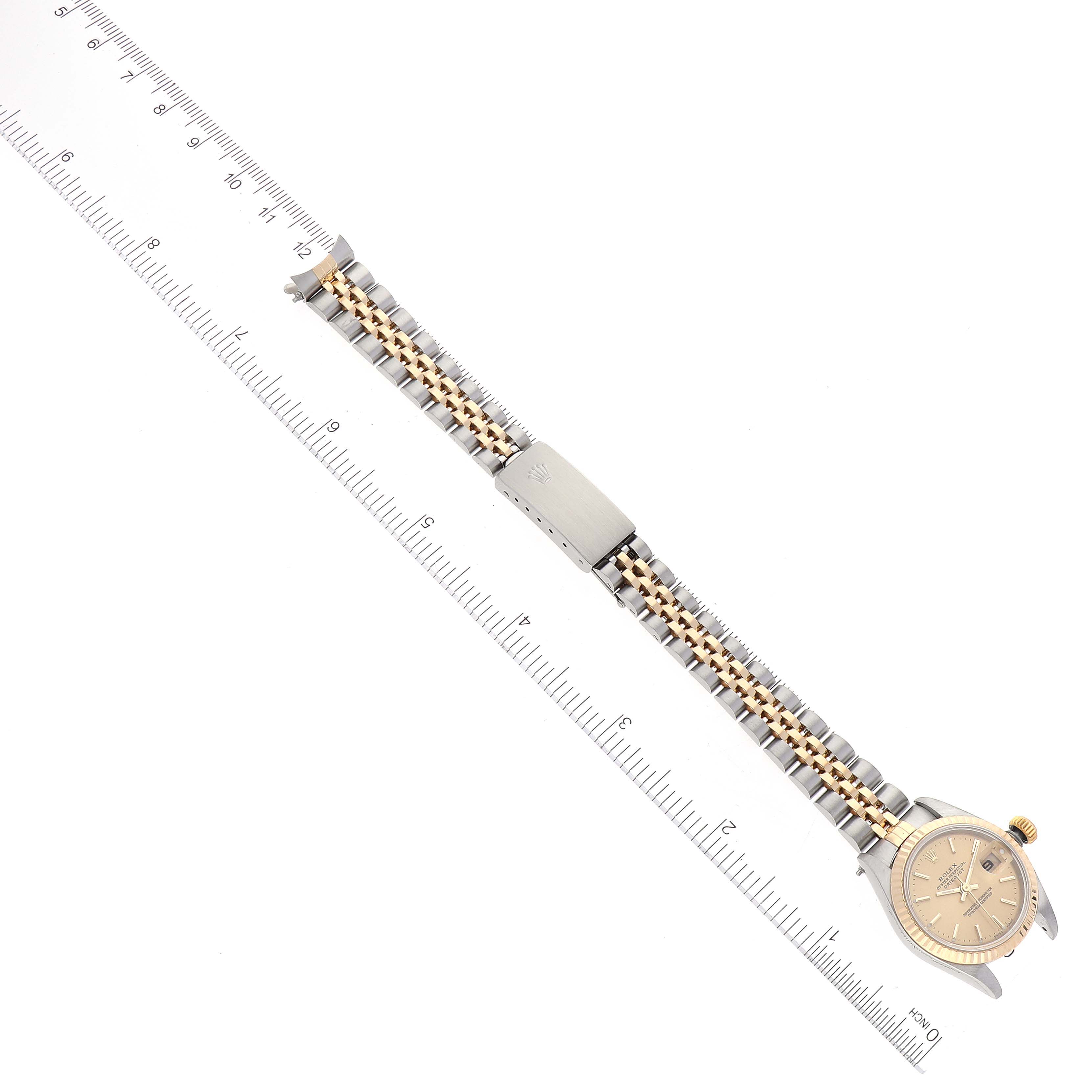 The Rolex Datejust 79173 Women's Steel and Gold (two tone) Champagne Dial 79173 Women's Steel and Gold (two tone) Champagne Dial watch is shown from an overhead angle, displaying the face and full bracelet with a ruler for scale.