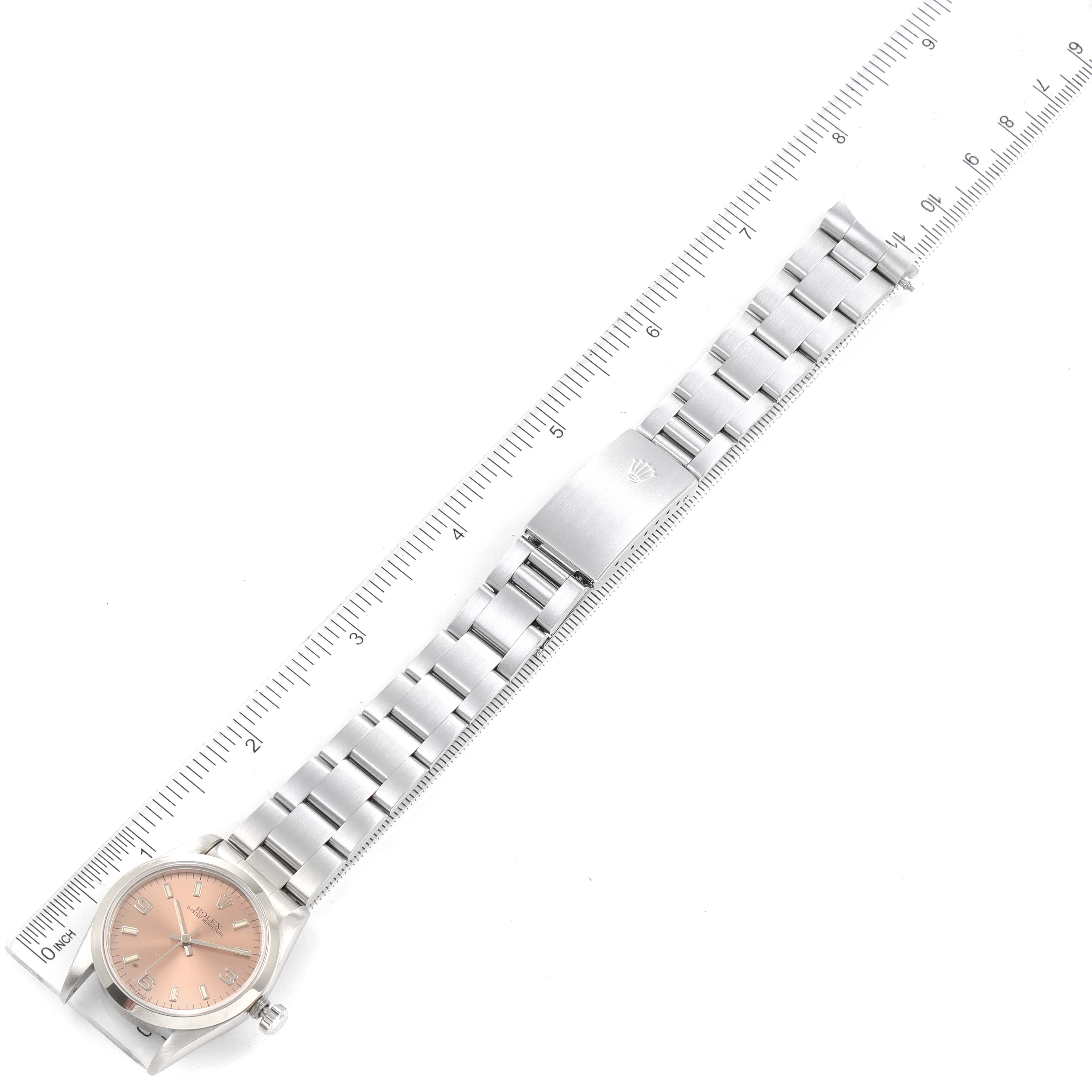 The image shows a full view of a Rolex Mid-Size 67480 Women
s Stainless Steel Pink Dial 67480 Women
s Stainless Steel Pink Dial watch laid flat with its dial and bracelet visible, and a ruler for scale.