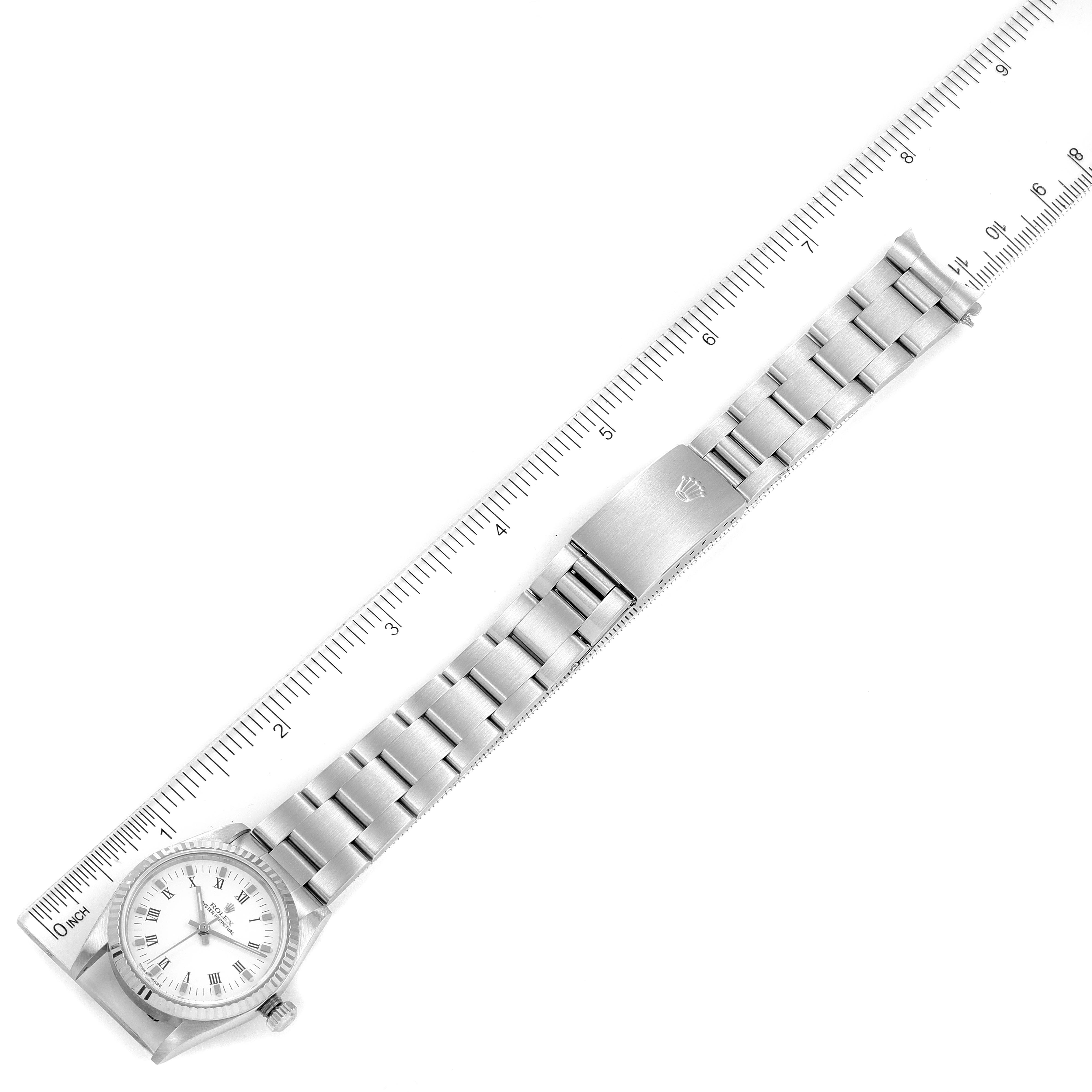 This image shows a top view of a mid-size Rolex watch with a stainless steel bracelet and an integrated clasp, measured against a ruler.