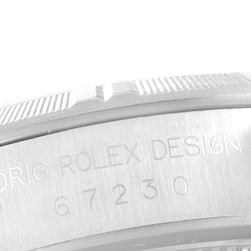 This image shows a close-up of the engraved bezel and case side of a Rolex Oyster Perpetual 67230 Women's Stainless Steel Grey Dial 67230 Women's Stainless Steel Grey Dial watch.