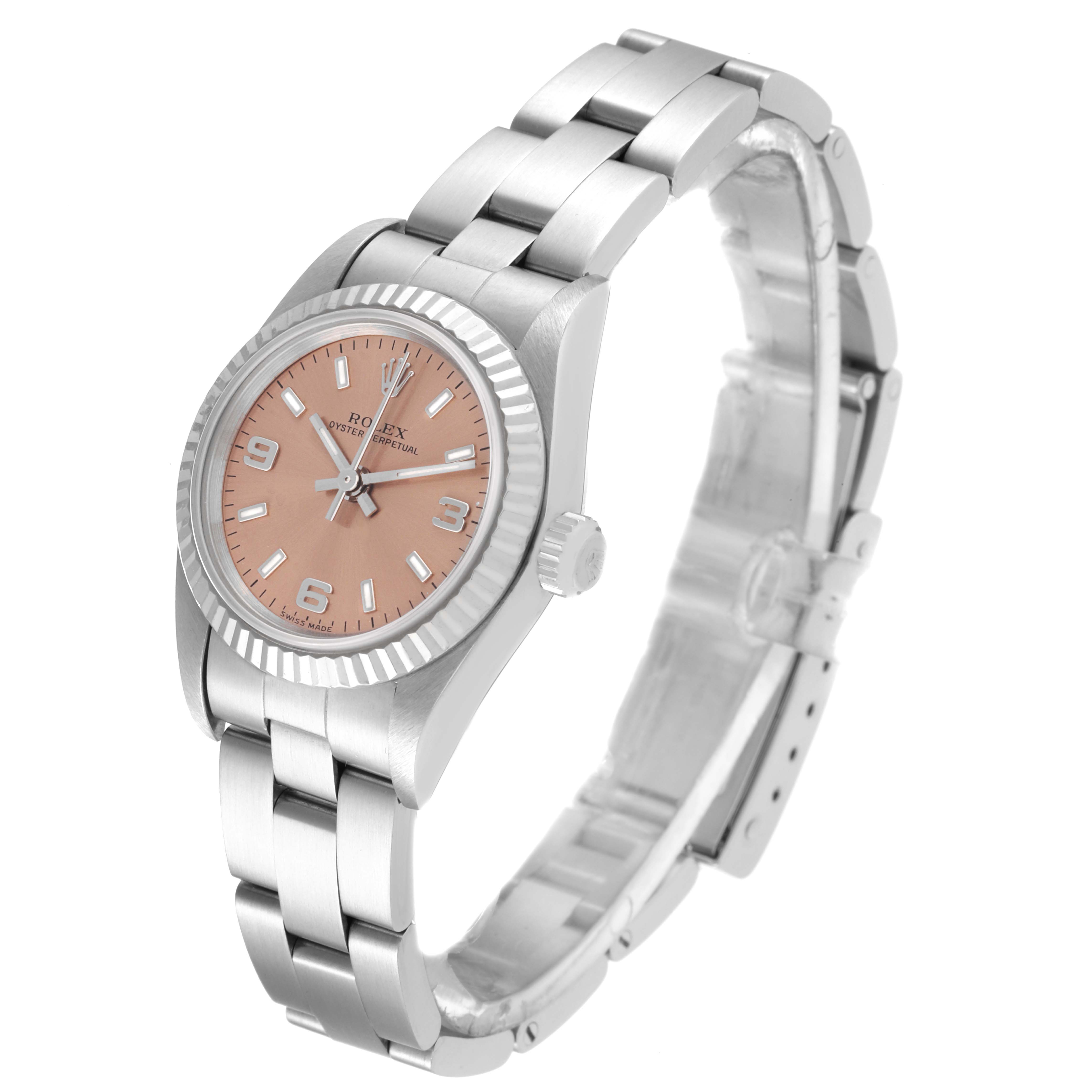 The image shows an angled view of a Rolex Oyster Perpetual 76094 Women
s Stainless Steel Pink Dial 76094 Women
s Stainless Steel Pink Dial watch, highlighting its pink dial, bezel, crown, and metal bracelet.