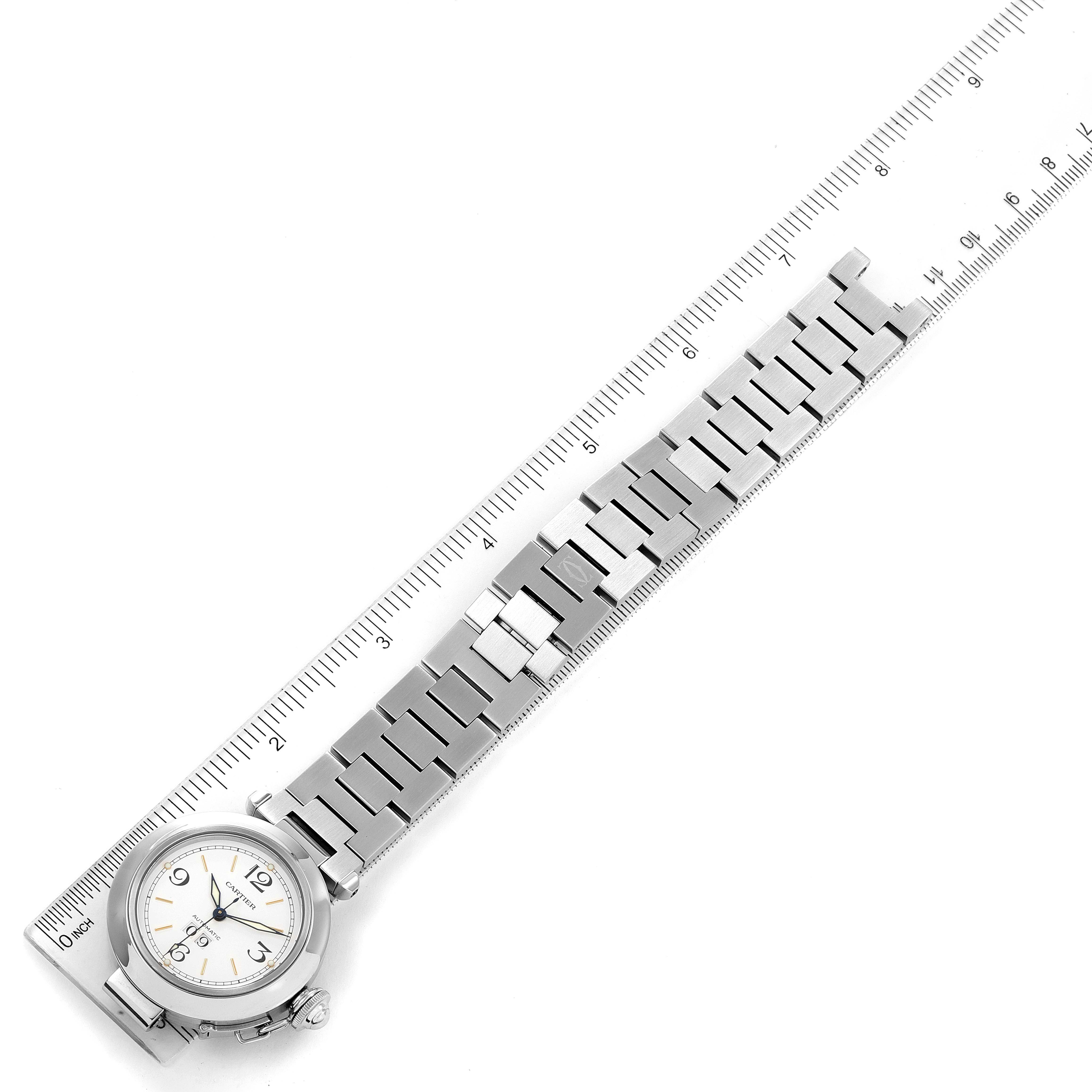 The image shows a Cartier Pasha W31044M7 Men's Stainless Steel White Dial W31044M7 Men's Stainless Steel White Dial watch laid out flat next to a ruler, highlighting its stainless steel bracelet and face.