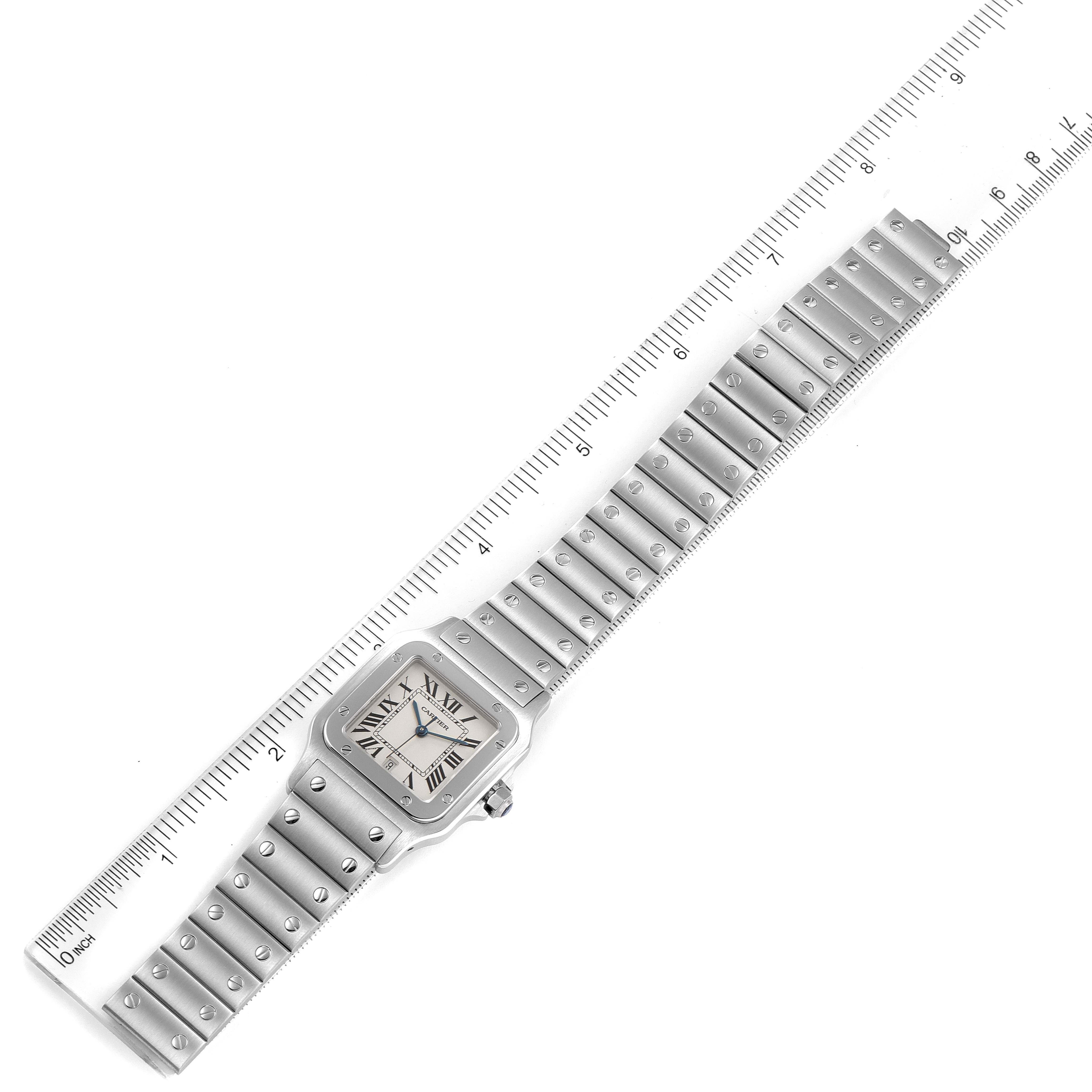 The image shows a top-down view of the Cartier Santos W20060D6 Men's Stainless Steel Silver Dial W20060D6 Men's Stainless Steel Silver Dial watch, including the face, bezel, and metal bracelet, alongside a ruler for scale.