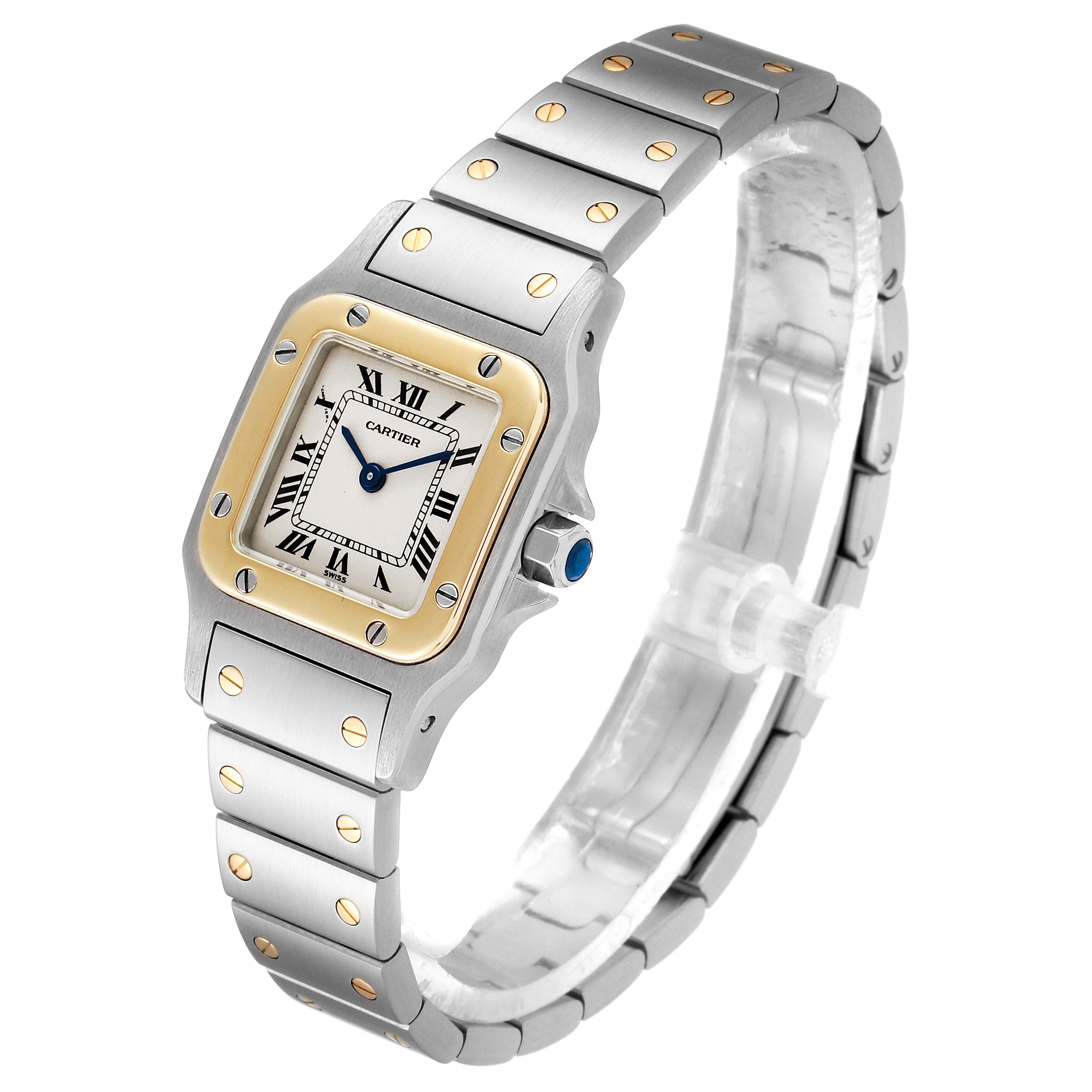 The image shows a side-angle view of a Cartier Santos W20012C4 Women
s Steel and Gold (two tone) Silver Dial W20012C4 Women
s Steel and Gold (two tone) Silver Dial watch, highlighting its square face, metal strap, and gold accents.