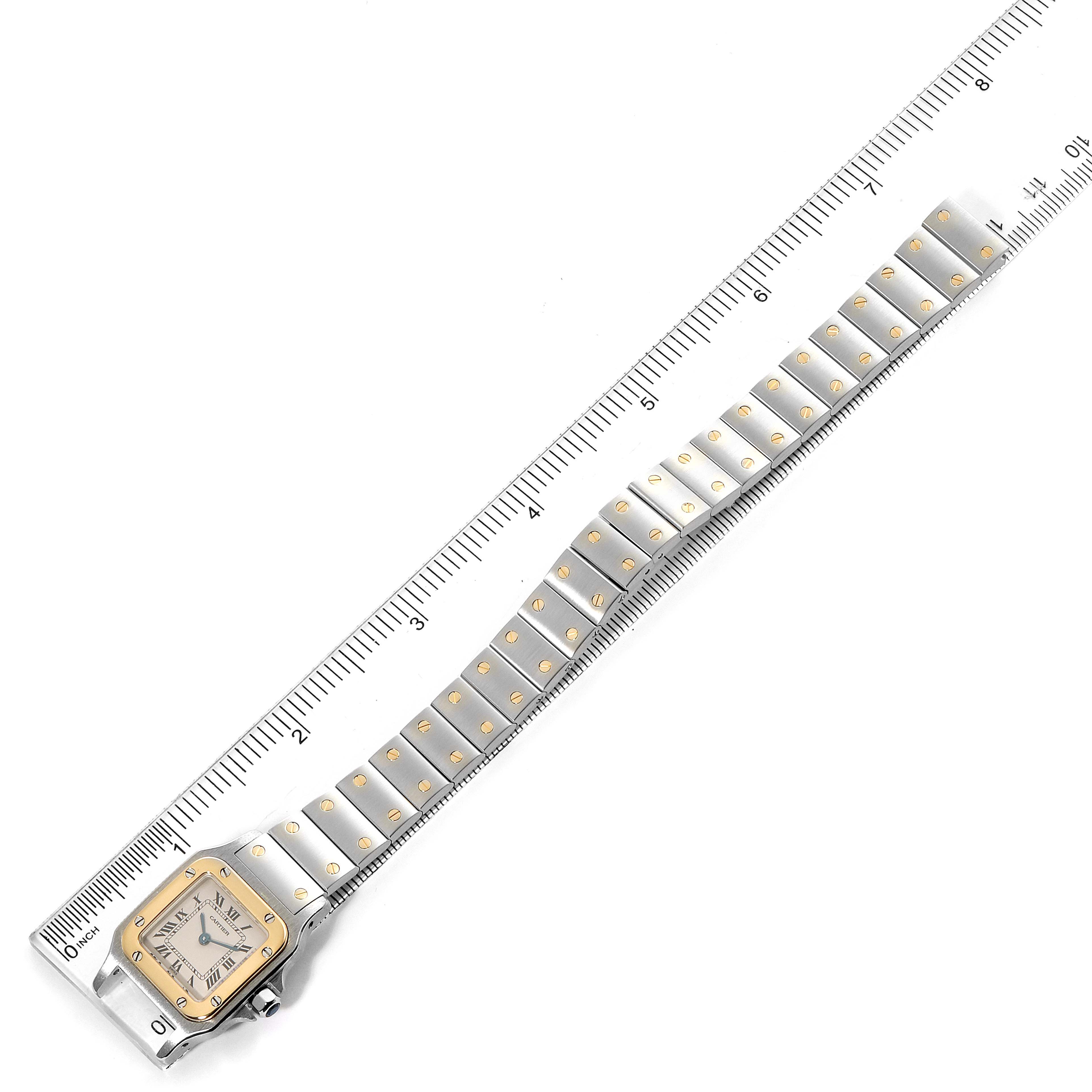 This image shows the full length of the Santos model watch by Cartier, with the face and bracelet in view, placed alongside a ruler.