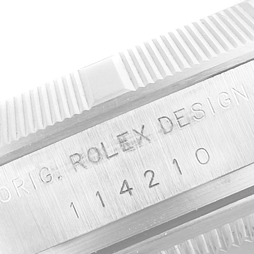 This close-up of the Rolex Air-King 114210 Men's Stainless Steel Blue Dial 114210 Men's Stainless Steel Blue Dial watch focuses on the model's engraved serial number and part of the bezel.