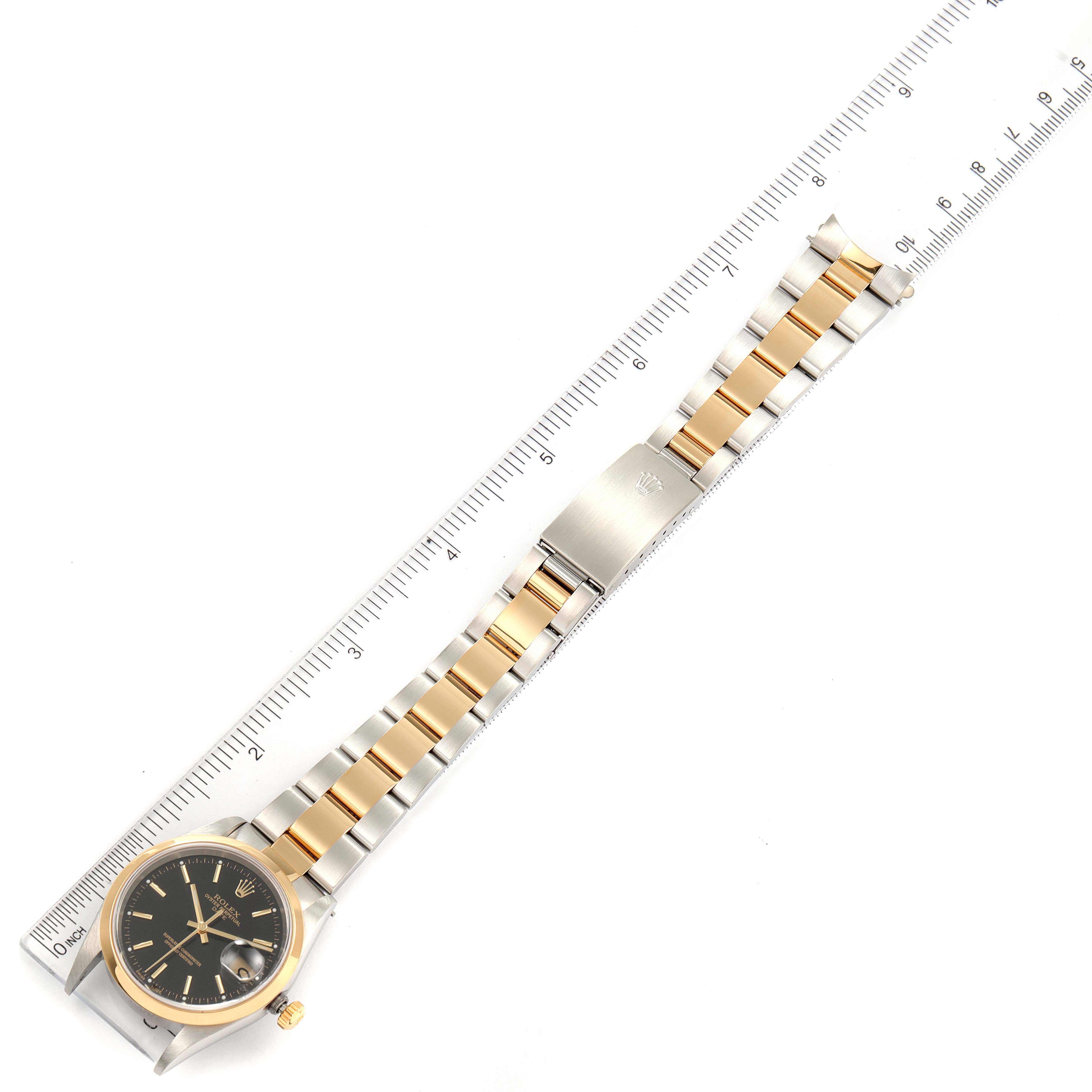 The image shows a Rolex Date 15203 Men's Steel and Gold (two tone) Black Dial 15203 Men's Steel and Gold (two tone) Black Dial model watch laid flat, with its bracelet fully extended and positioned alongside a ruler for scale.