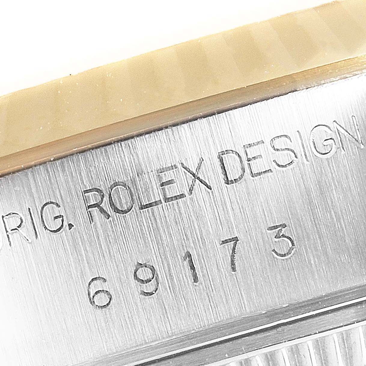 This close-up image of the Rolex Datejust 69173 Women's Steel and Gold (two tone) Champagne Dial 69173 Women's Steel and Gold (two tone) Champagne Dial watch shows the engraved model number and "ROLEX DESIGN" on the case side.