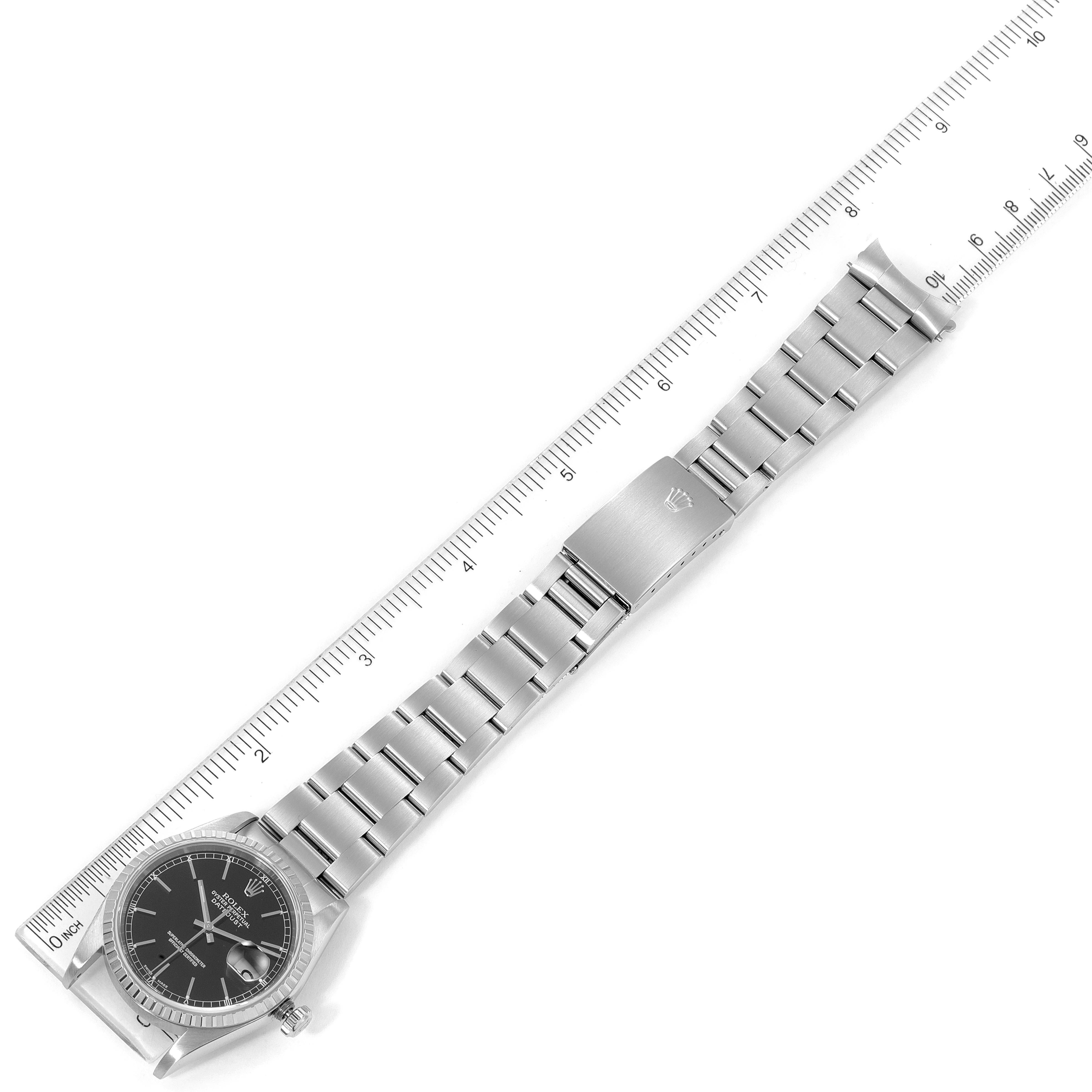 This image shows a top view of a Rolex Datejust 16220 Men's Stainless Steel Black Dial 16220 Men's Stainless Steel Black Dial watch laid next to a ruler, displaying its face, bracelet, and clasp.