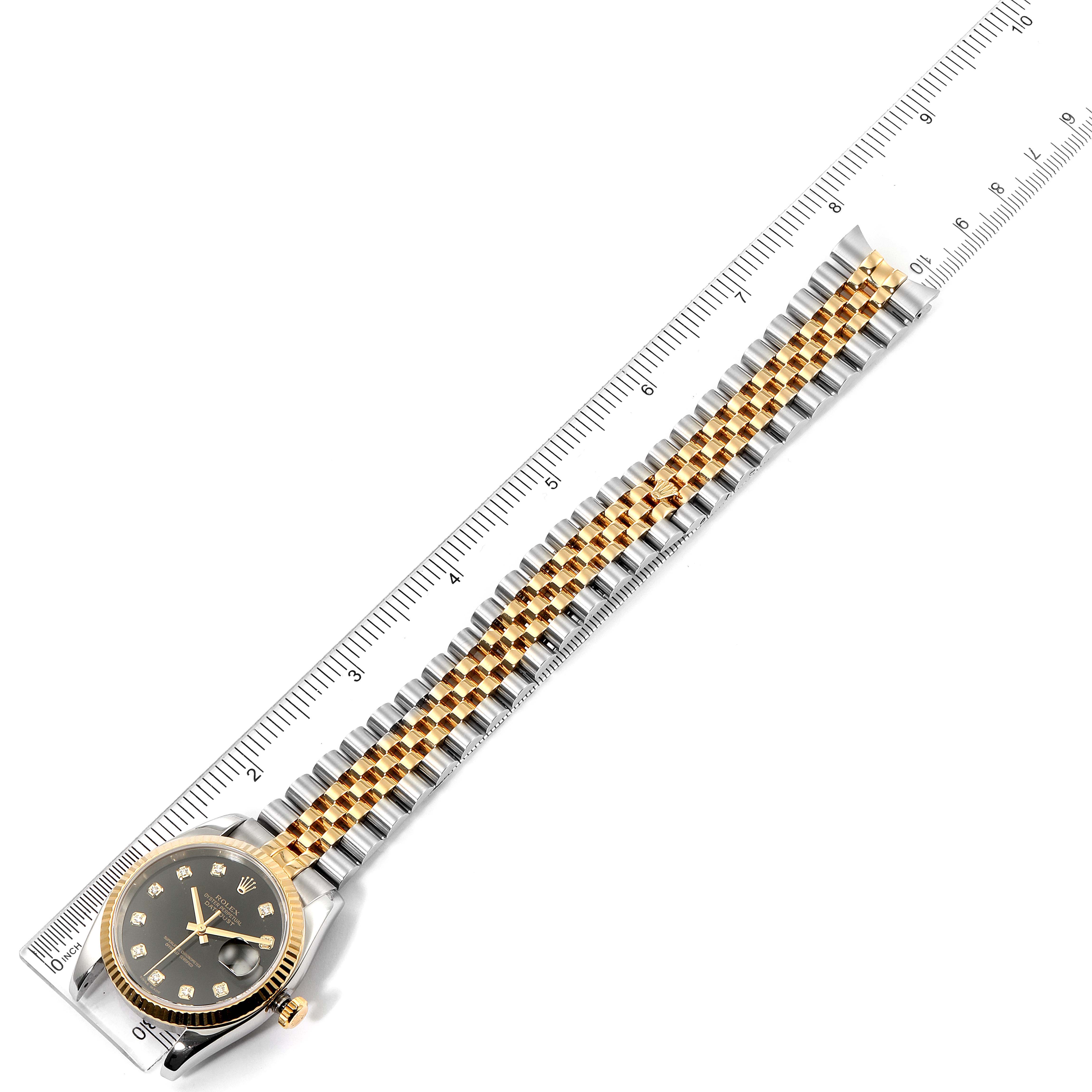 The image shows a Rolex Datejust 116233 Men's Steel and Gold (two tone) Black Dial 116233 Men's Steel and Gold (two tone) Black Dial watch laid flat on a ruler, displaying the face and full length of the strap.