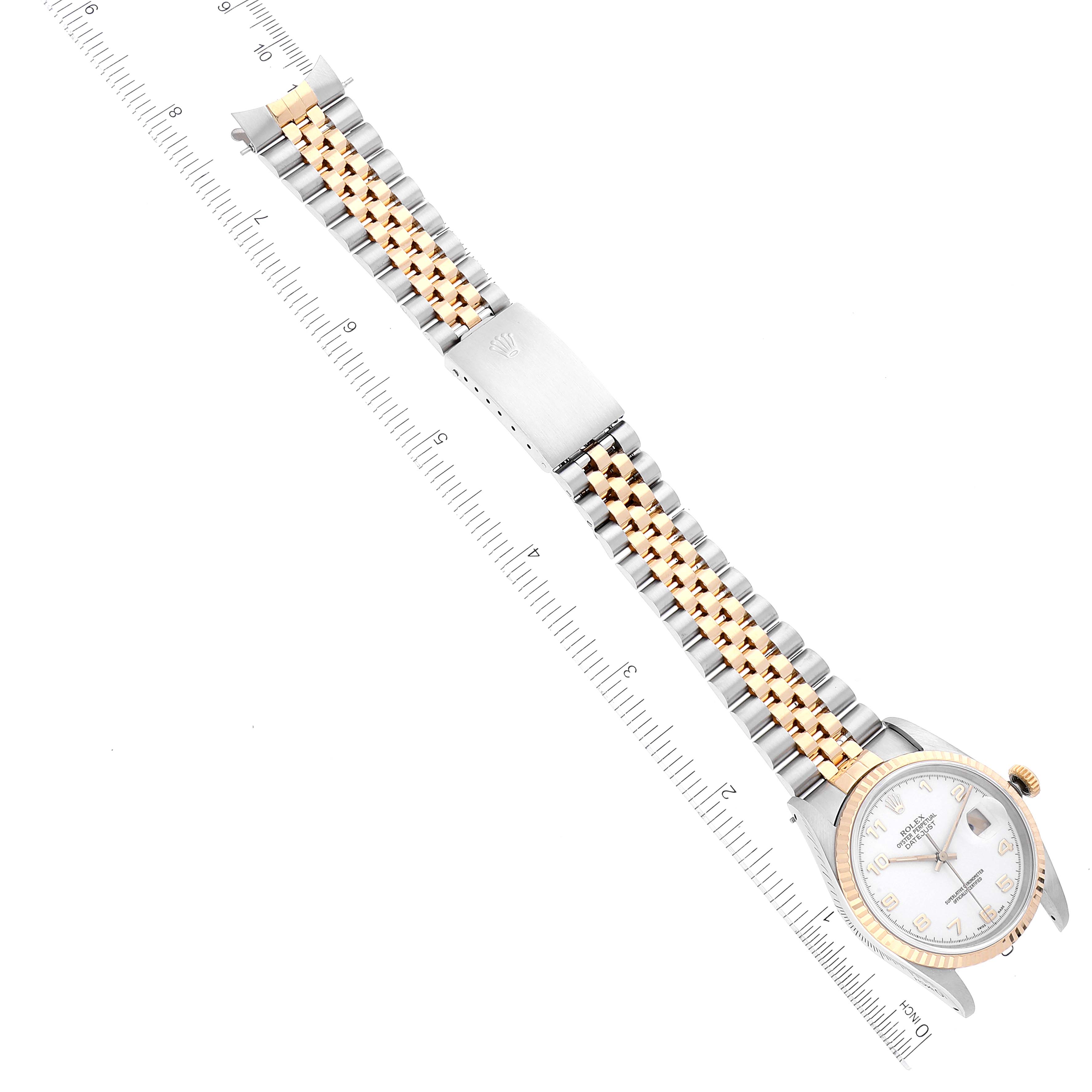 The image shows a top-down view of a Rolex Datejust 16233 Men's Steel and Gold (two tone) White Dial 16233 Men's Steel and Gold (two tone) White Dial watch highlighting the face, bezel, and two-tone bracelet with a measuring ruler.