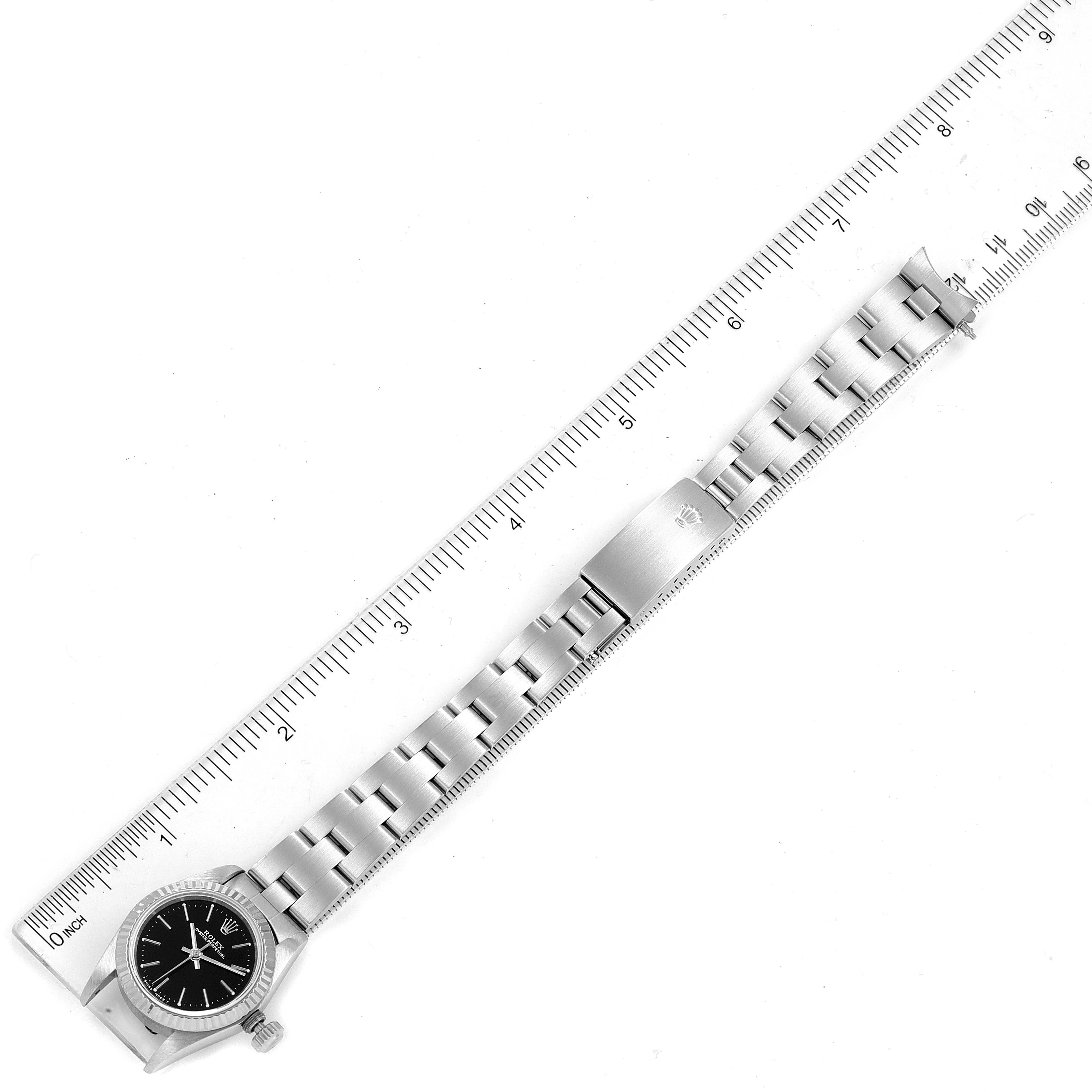 The image shows a Rolex Oyster Perpetual 67194 Women's Stainless Steel Black Dial 67194 Women's Stainless Steel Black Dial watch laid flat next to a ruler, displaying the entire band and face from a top-down angle.