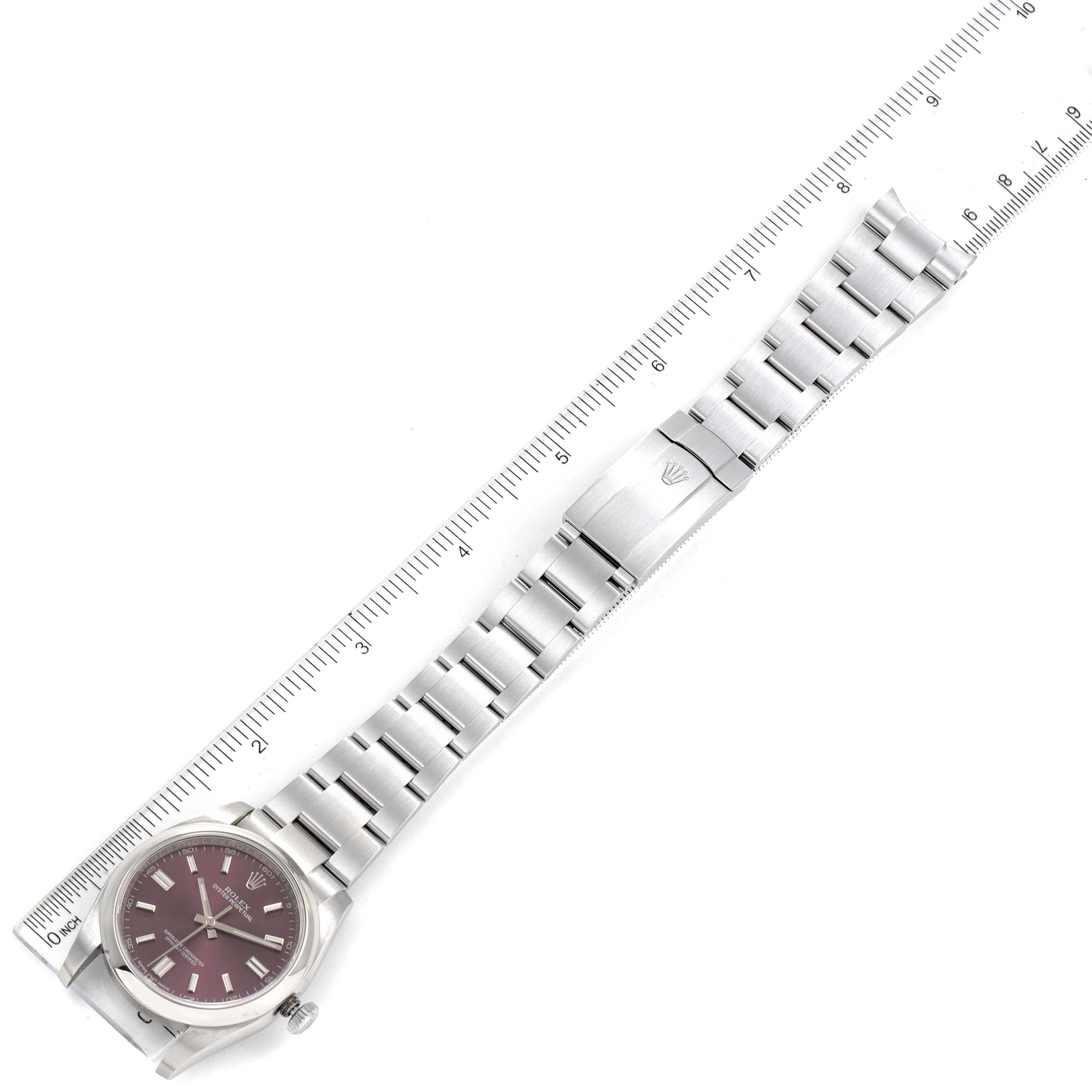 The image shows a top-down view of a Rolex Oyster Perpetual 116000 Men's Stainless Steel Burgundy Dial 116000 Men's Stainless Steel Burgundy Dial watch with a full bracelet and a measuring ruler beside it.