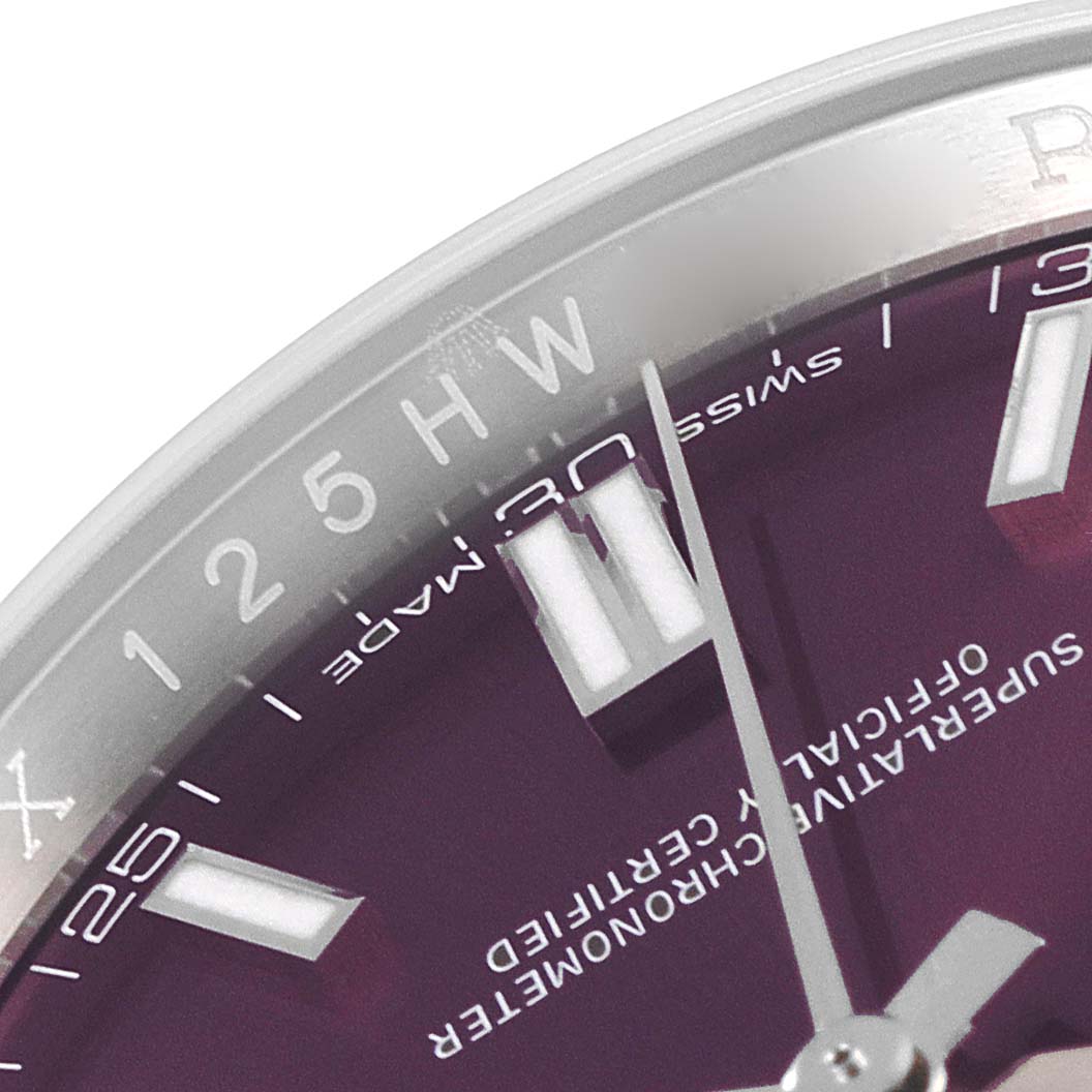 This close-up image of a Rolex Oyster Perpetual 116000 Men's Stainless Steel Burgundy Dial 116000 Men's Stainless Steel Burgundy Dial model shows part of the dial, including the hour markers and hands, with some text.