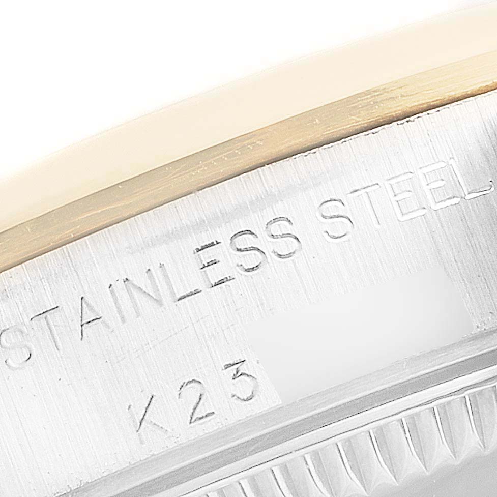The image shows a close-up of the edge of a Rolex Oyster Perpetual 76183 Women's Steel and Gold (two tone) Grey Dial 76183 Women's Steel and Gold (two tone) Grey Dial watch case with "STAINLESS STEEL" and "K23" engraved.