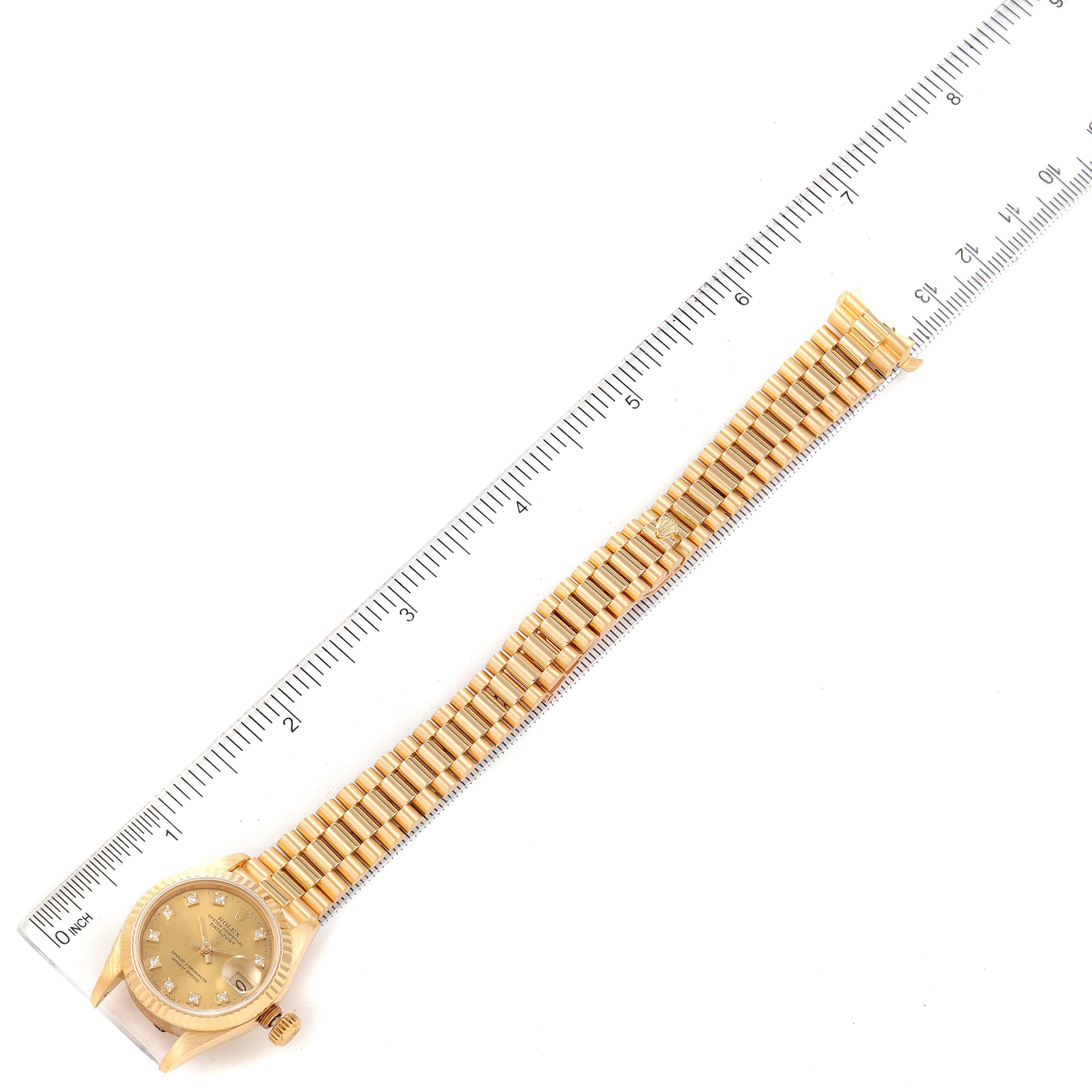 The image shows a Rolex President 69178 Women's Yellow Gold Champagne Dial 69178 Women's Yellow Gold Champagne Dial model watch laid flat next to a ruler for measurement, displaying the entire band and face.