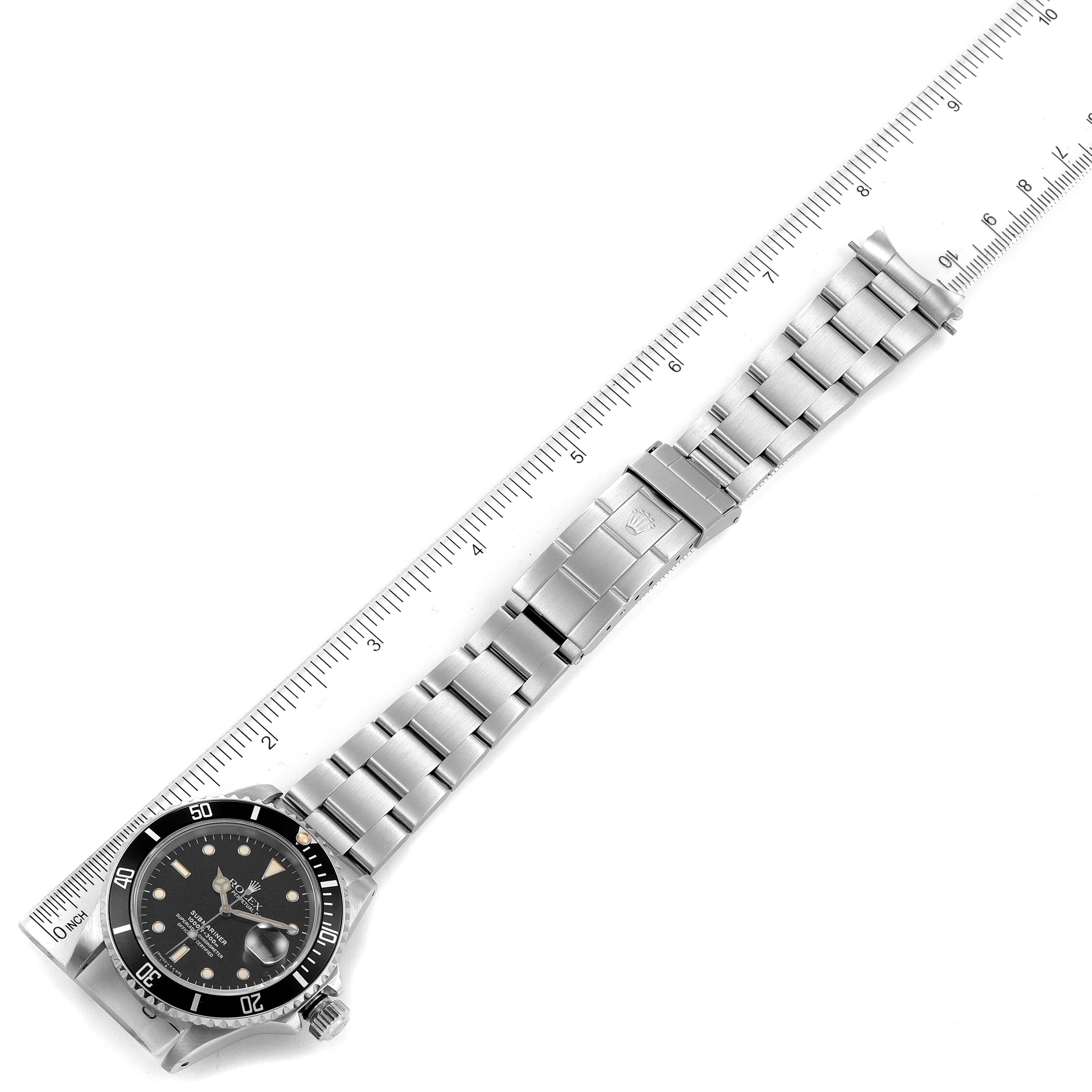 The image shows a Rolex Submariner 16610 Men's Stainless Steel Black Dial 16610 Men's Stainless Steel Black Dial watch positioned diagonally with its bracelet and clasp fully extended next to a ruler.