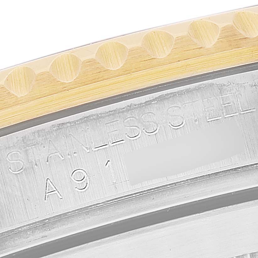 This close-up image of a Rolex Submariner 16613 Men's Steel and Gold (two tone) Blue Dial 16613 Men's Steel and Gold (two tone) Blue Dial shows part of the bezel and engraved serial numbers on the stainless steel case.