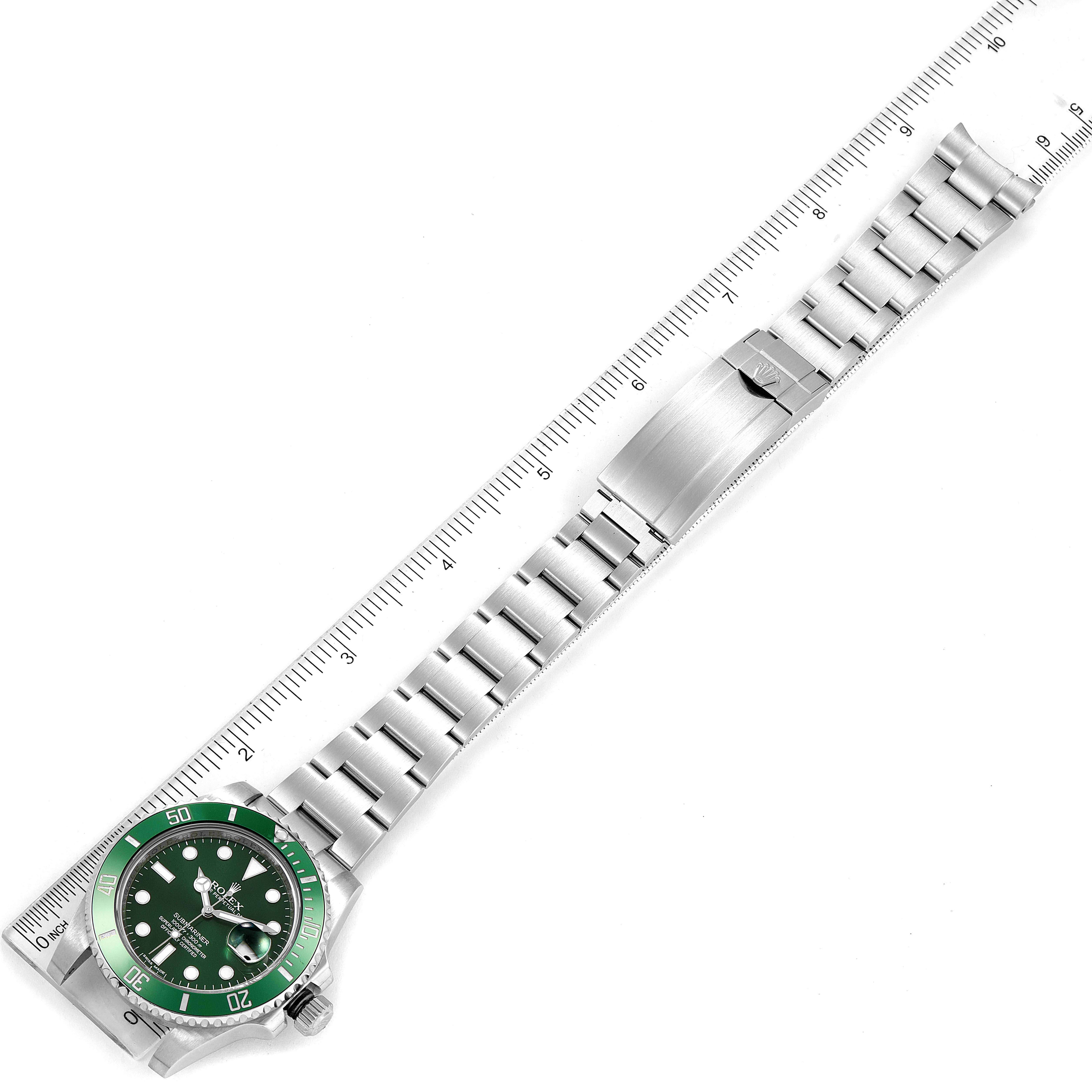 The image shows a top-down view of a Rolex Submariner 116610LV Men
s Stainless Steel Green Dial 116610LV Men
s Stainless Steel Green Dial watch with a green bezel and bracelet extended alongside a ruler.