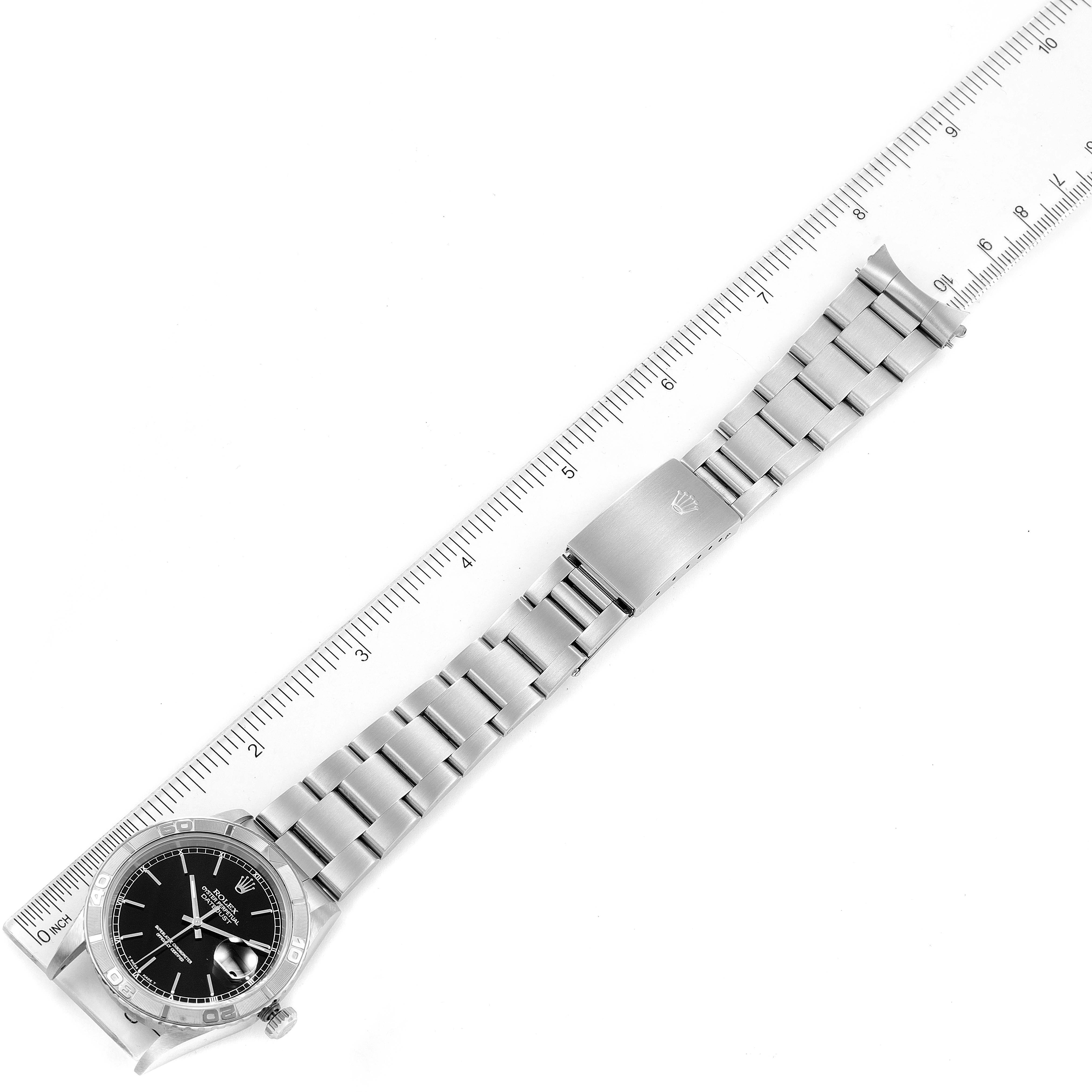 The Rolex Turn-o-Graph 16264 Men's Stainless Steel Black Dial 16264 Men's Stainless Steel Black Dial watch is shown at a top-down angle, displaying the entire watch and metal bracelet next to a ruler for scale.