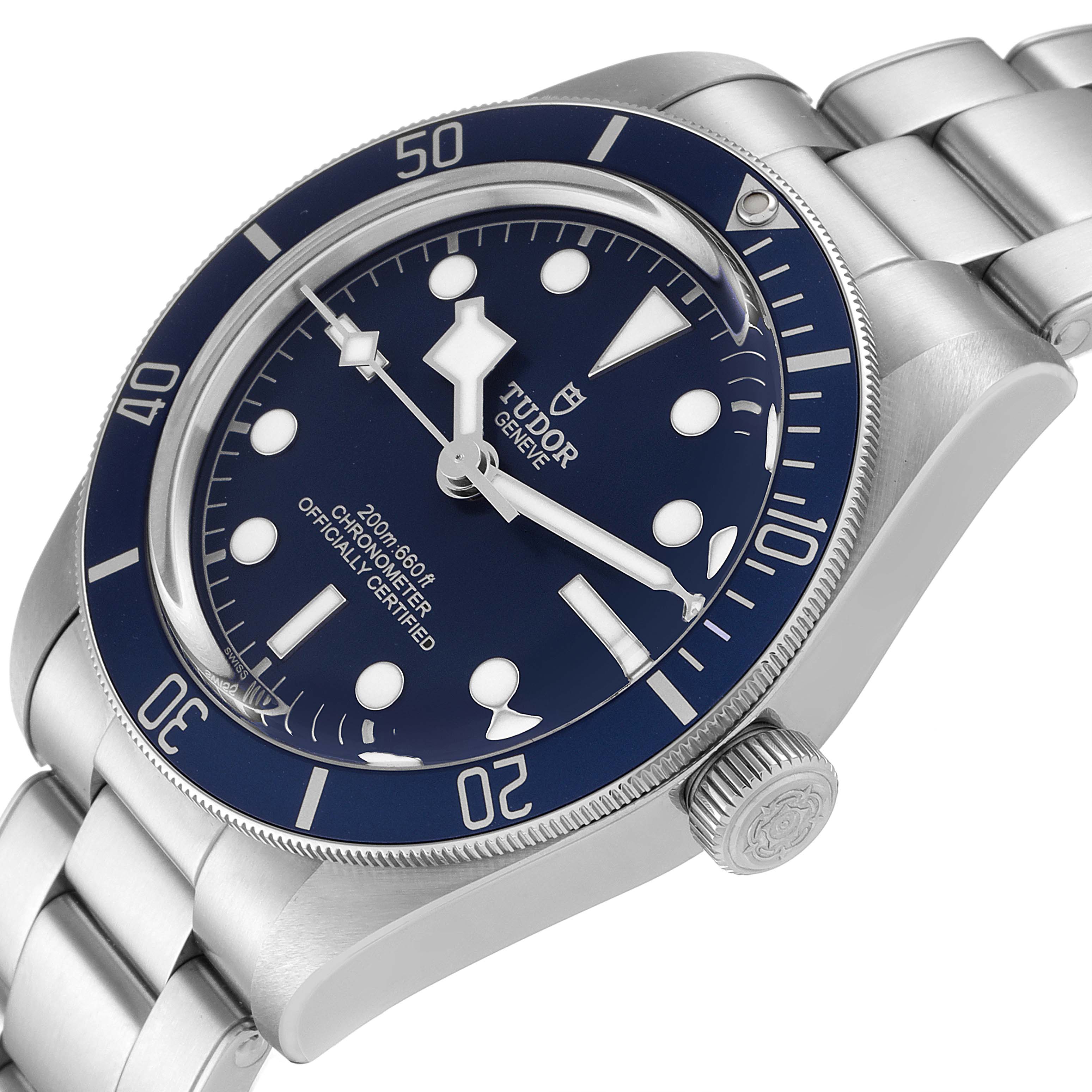 The Heritage Black Bay by Tudor is shown at an angled top view, highlighting its blue dial, bezel, and stainless steel bracelet.