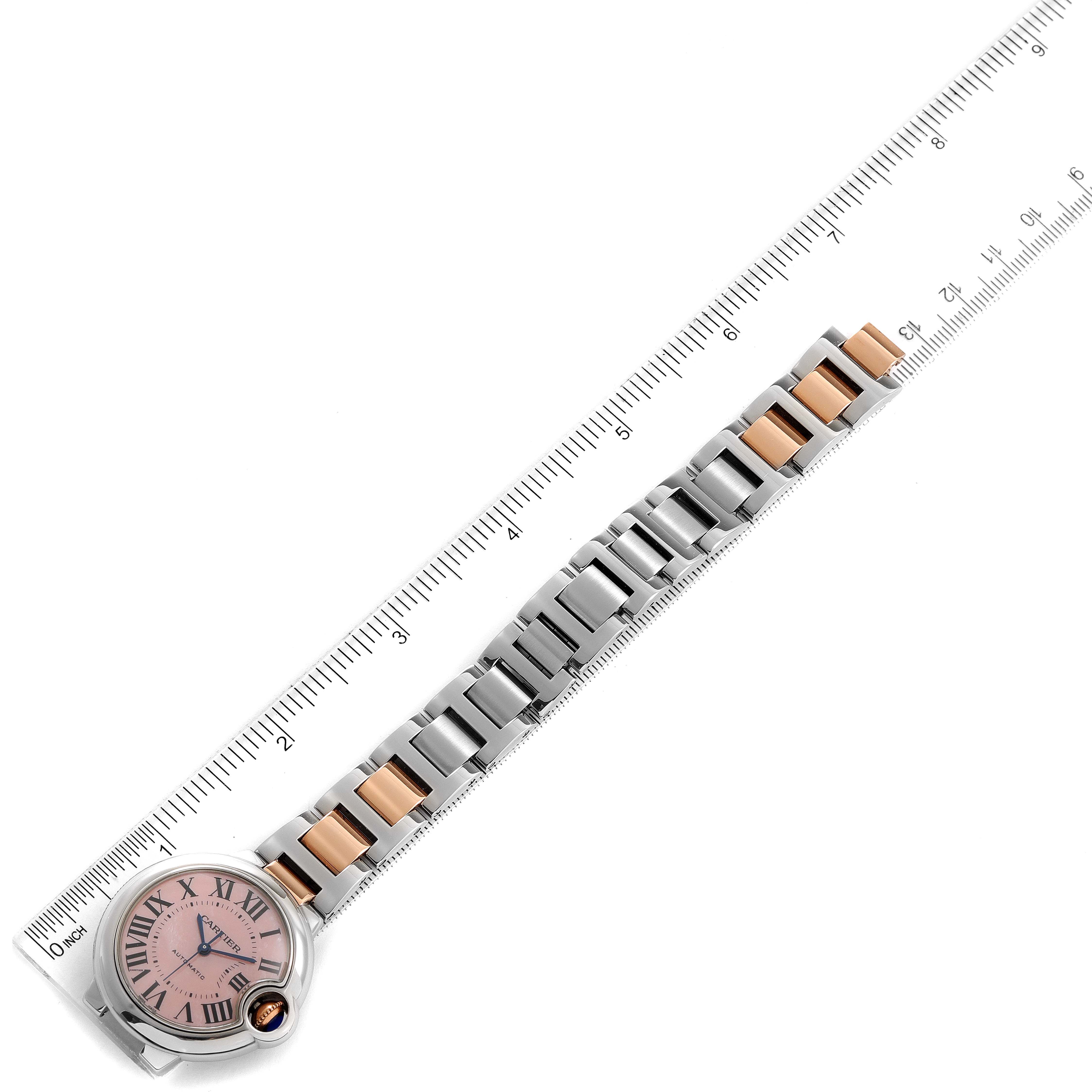 The Cartier Ballon Bleu W6920098 Women's Steel and Gold (two tone) Mother of Pearl Dial W6920098 Women's Steel and Gold (two tone) Mother of Pearl Dial watch is displayed from an top-down angle with a ruler beside it for measurement.