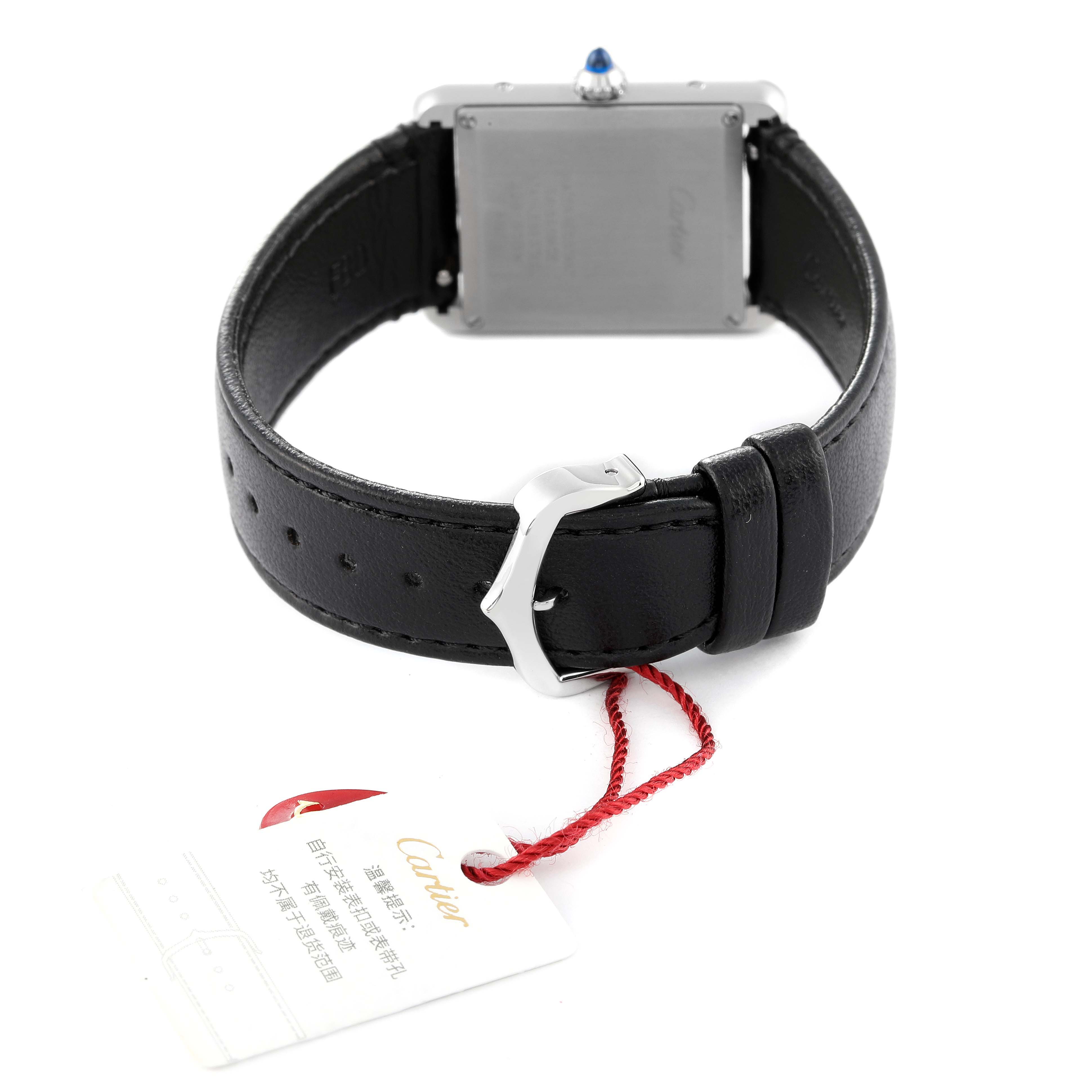 This image shows the back view of a Cartier Tank Must WSTA0059 Women's Stainless Steel Silver Dial WSTA0059 Women's Stainless Steel Silver Dial watch, featuring its black leather strap and a tag attached to it.