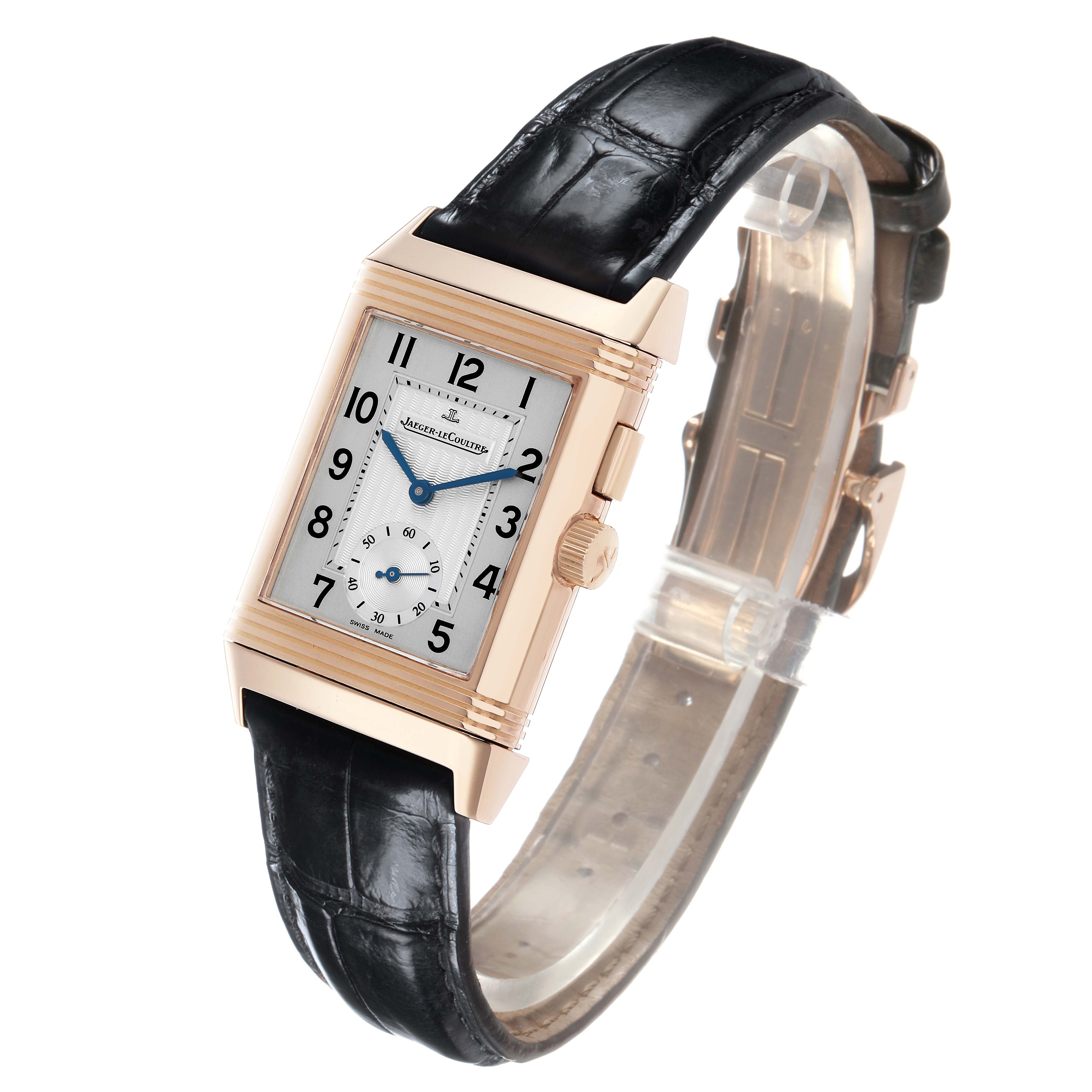 The Jaeger-LeCoultre Reverso watch is shown from a three-quarter angle, displaying the dial, crown, and leather strap.