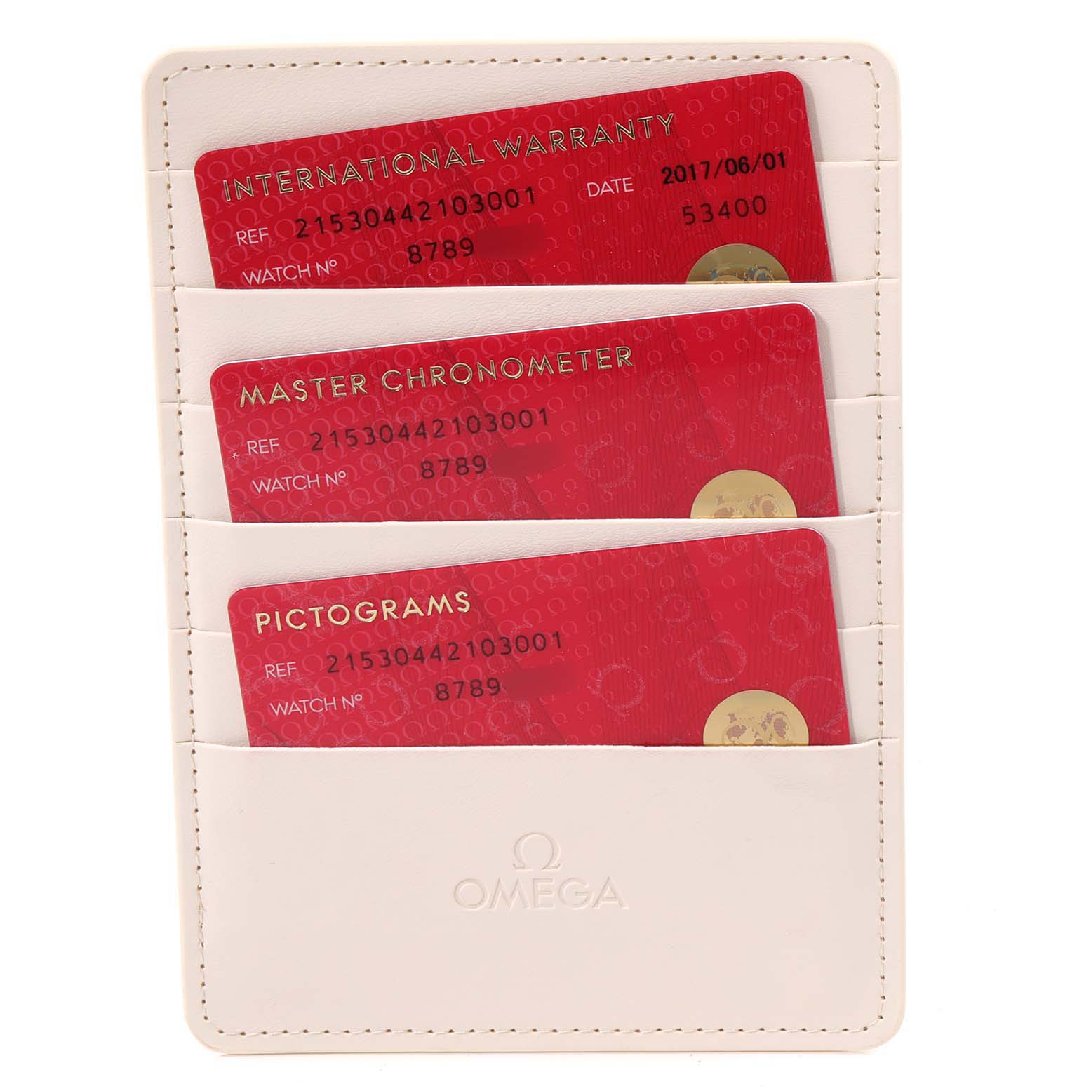 The image shows a white Omega cardholder with three red cards labeled International Warranty, Master Chronometer, and Pictograms.