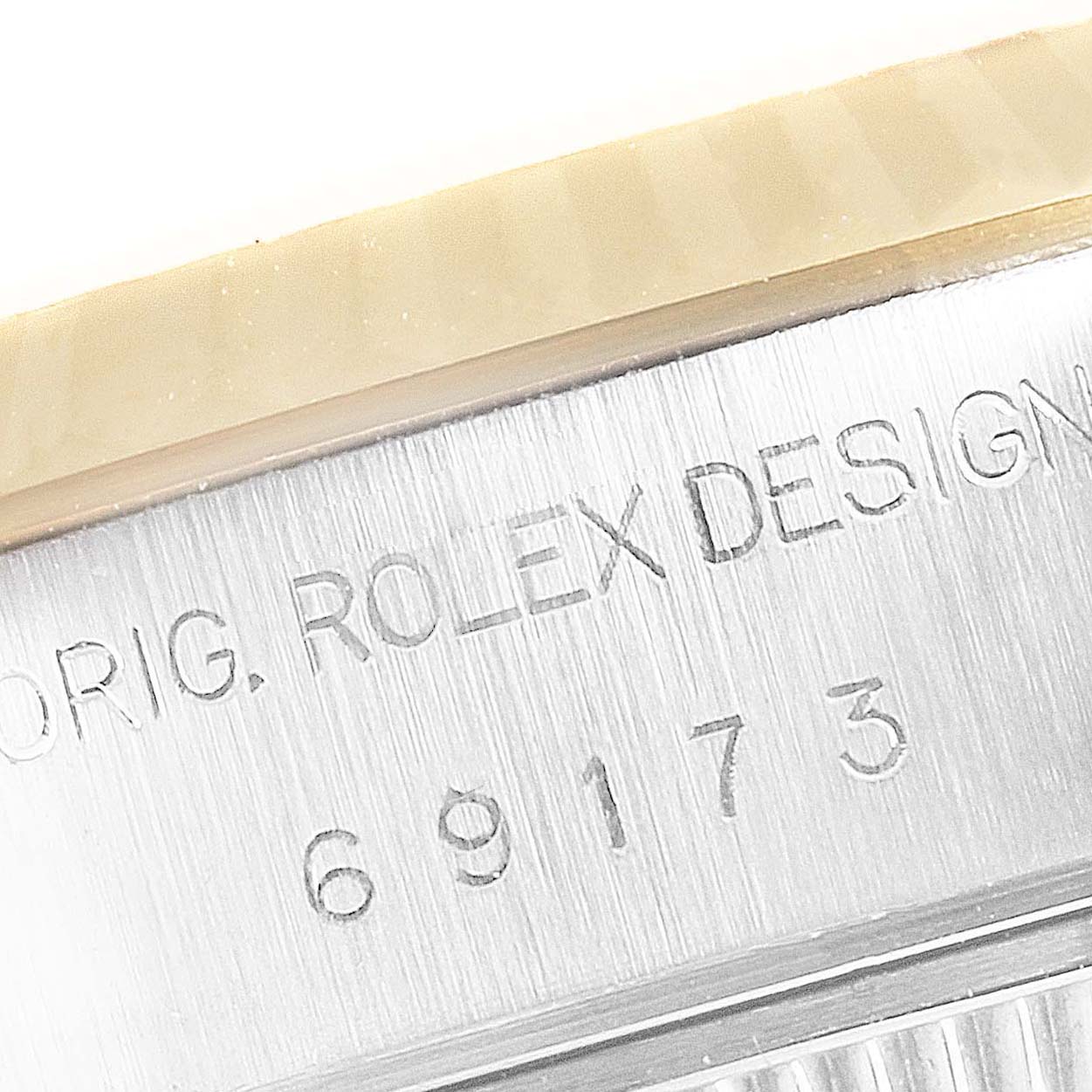 The image shows a close-up of the side of a Rolex Datejust 69173 Women's Steel and Gold (two tone) Blue Dial 69173 Women's Steel and Gold (two tone) Blue Dial watch, highlighting the engraved serial number and "Rolex Design" text.