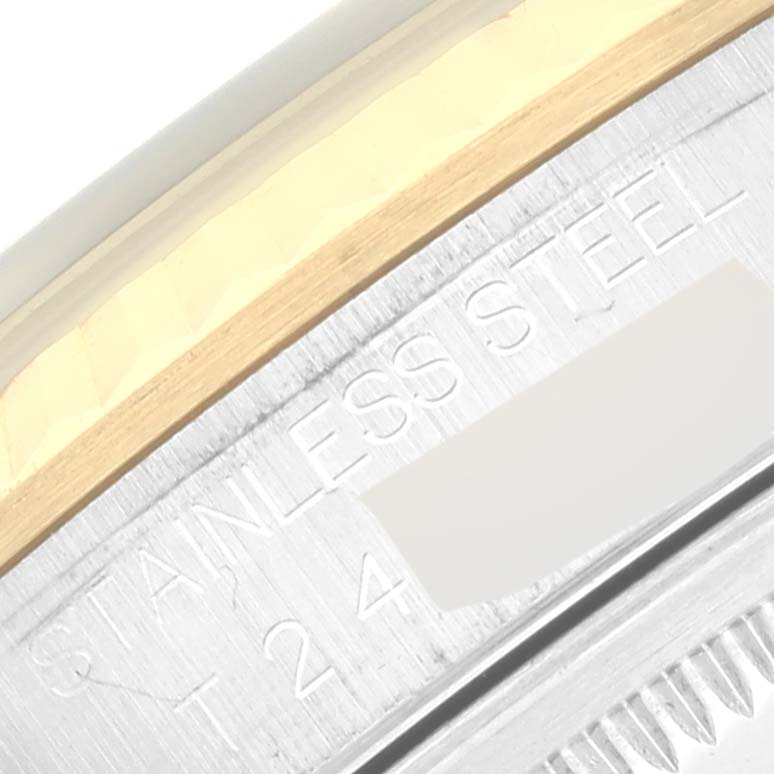 This close-up image of the Rolex Datejust 16233 Men's Steel and Gold (two tone) Blue Dial 16233 Men's Steel and Gold (two tone) Blue Dial watch shows the engraved text on its stainless steel case alongside a gold component.