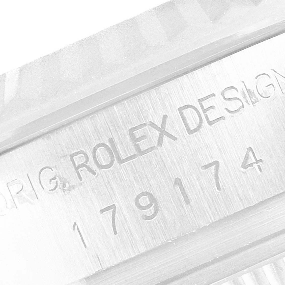 The image shows a close-up of the Rolex Datejust 179174 Women's Stainless Steel Blue Dial 179174 Women's Stainless Steel Blue Dial model's serial number and "Rolex Design" engraving on the watch bezel.