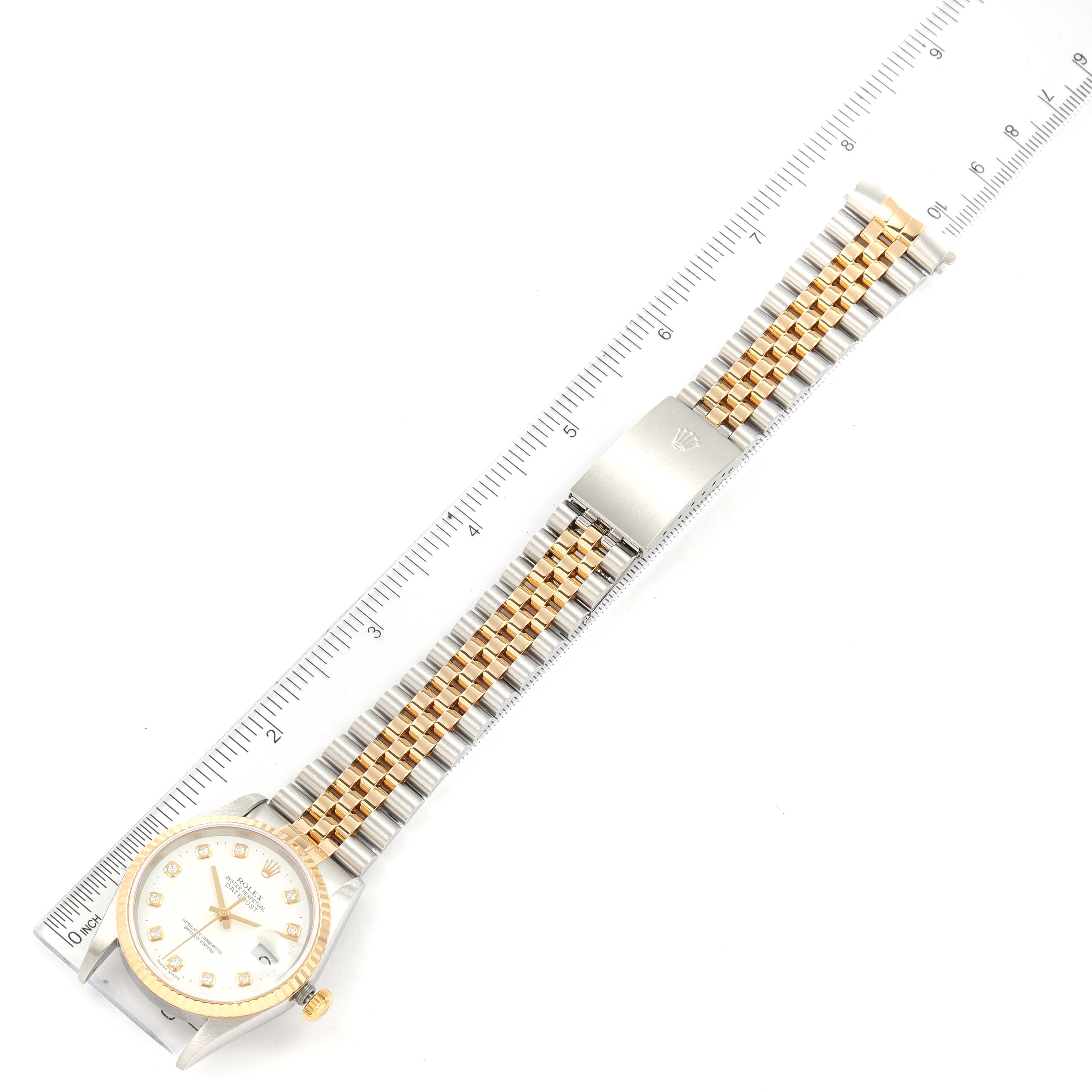 This overhead view shows the face, dial, and bracelet of a Rolex Datejust 16233 Men's Steel and Gold (two tone) White Dial 16233 Men's Steel and Gold (two tone) White Dial watch, alongside a ruler for scale.