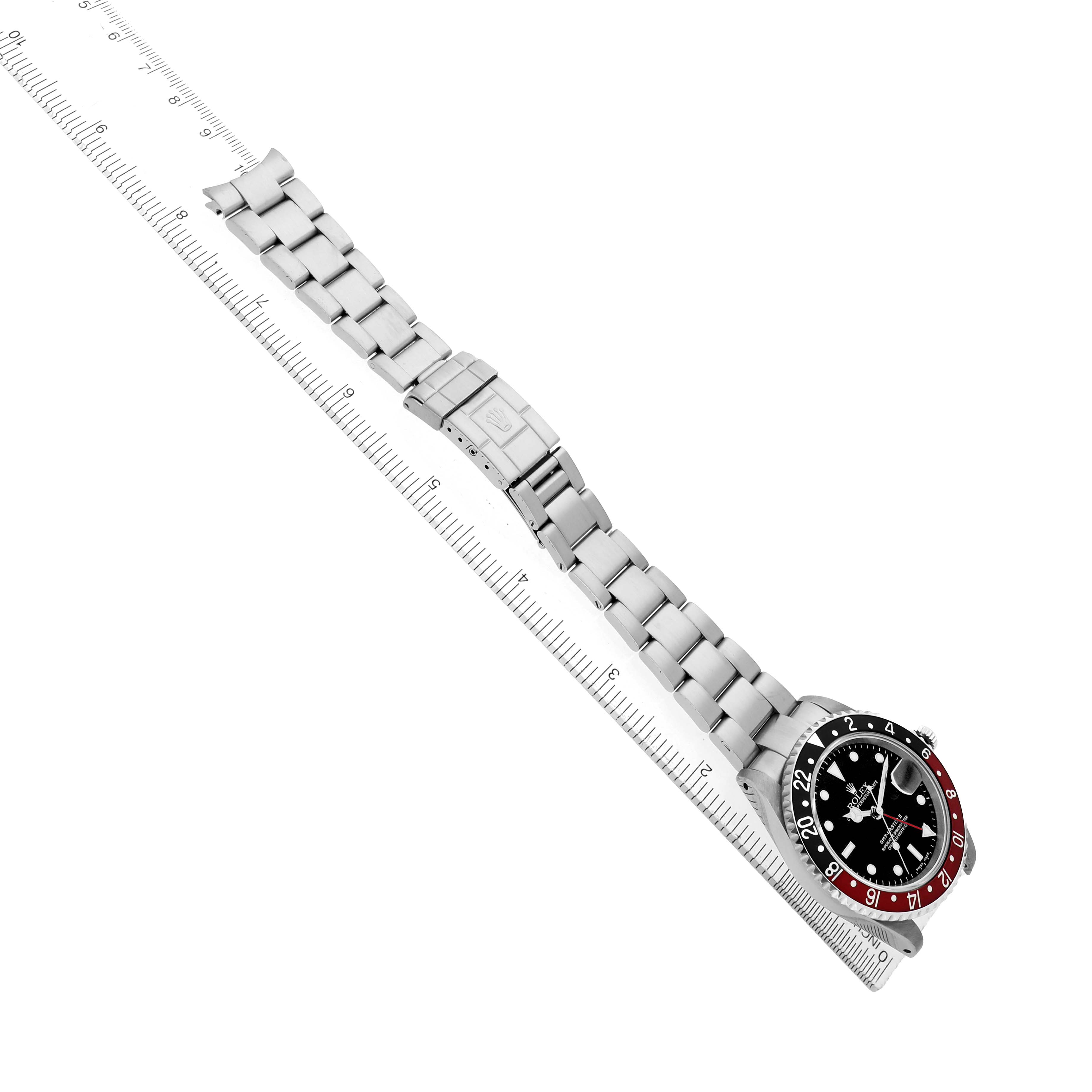 The Rolex GMT-Master 16710 Men's Stainless Steel Black Dial watch is shown at a diagonal angle, displaying the face, bezel, bracelet, and clasp alongside a ruler.