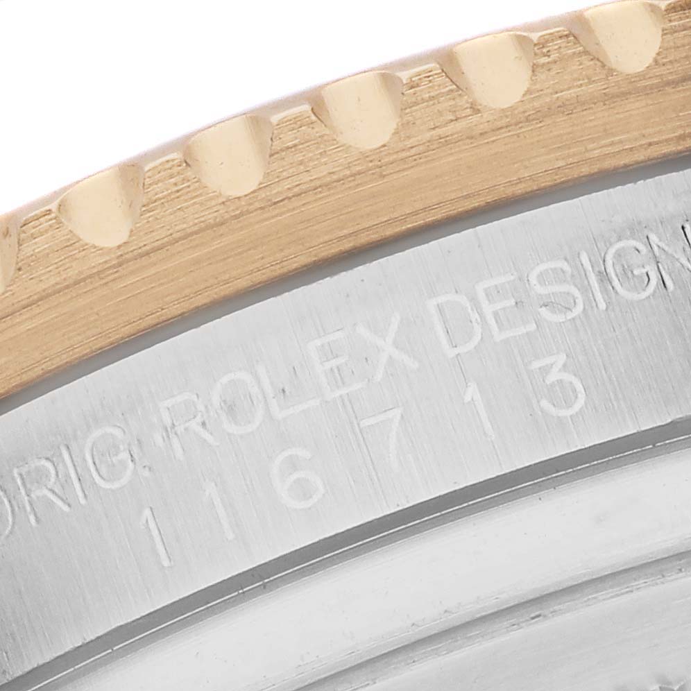 The image shows a close-up of the Rolex GMT-Master 116713 Men's Steel and Gold (two tone) Black Dial model's bezel and engraved case details.