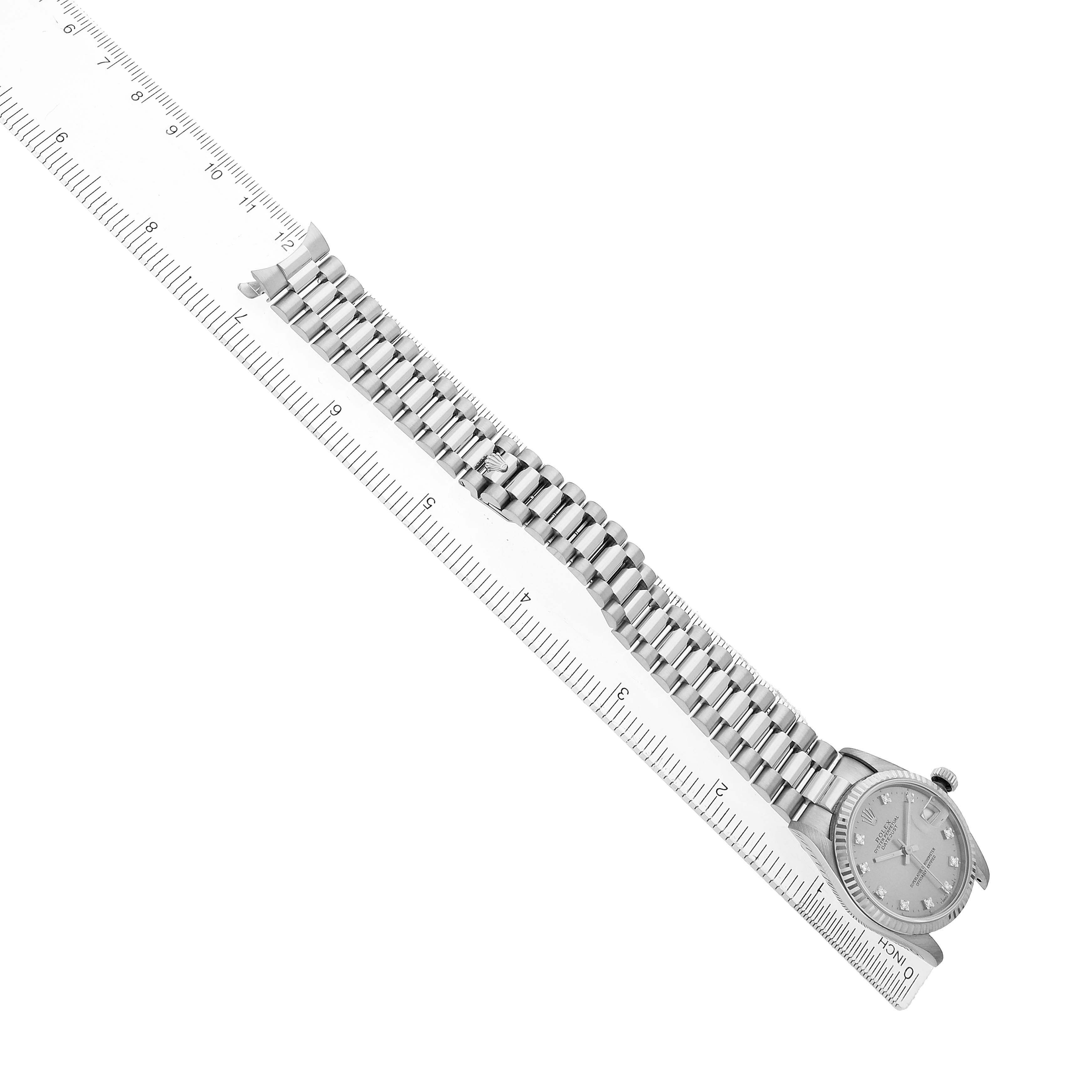 The image shows a side view of a Rolex President 68279 Women's White Gold Silver Dial watch with its band fully extended alongside a ruler for scale.